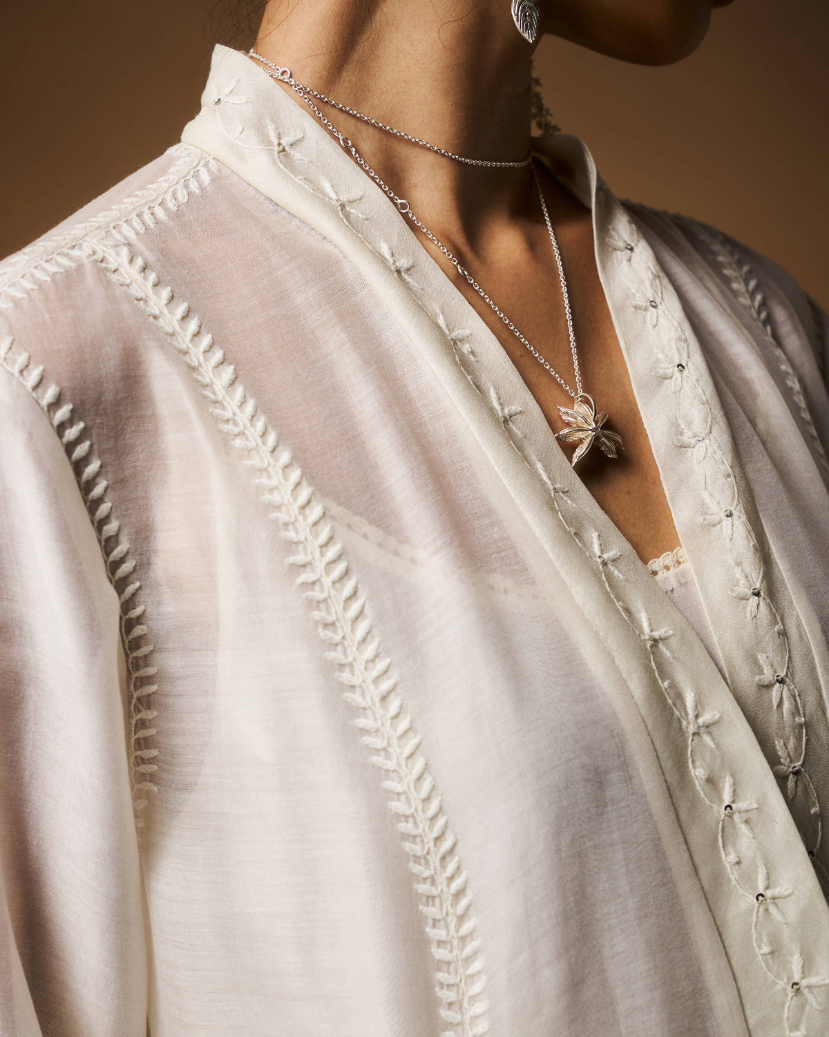 Close-up of white chikankari embroidery on an ivory Pavi overlay neckline.