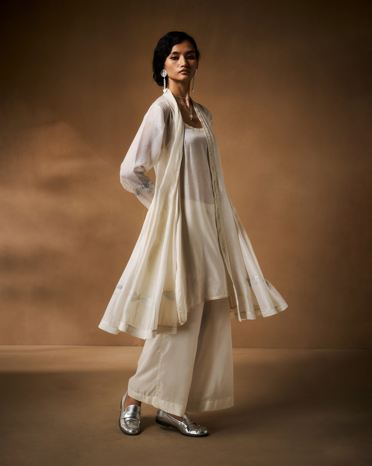 Person wearing a sheer ivory Pavi overlay with a flared open front.