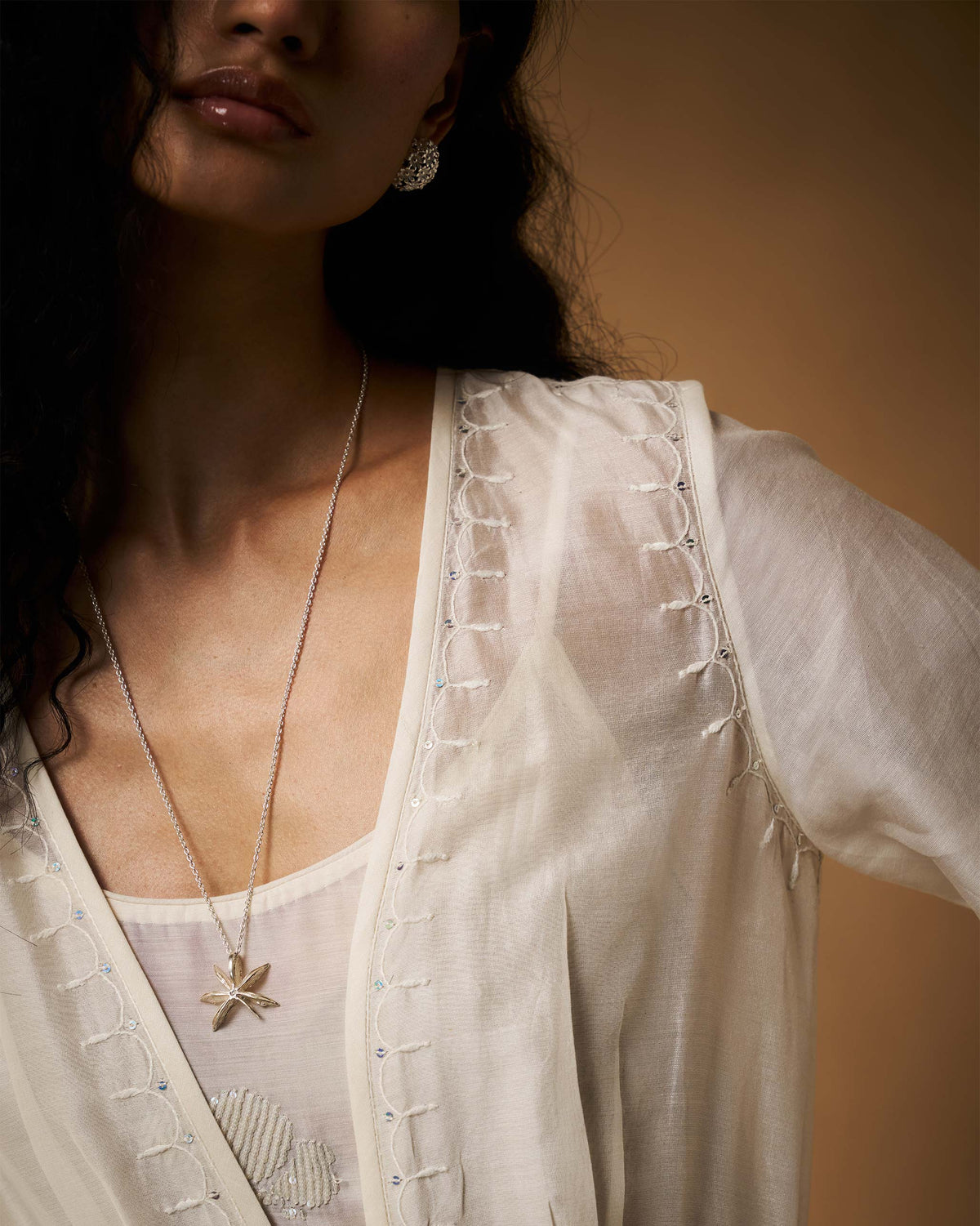 Close-up of embroidery on an ivory Nazaha overlay neckline.