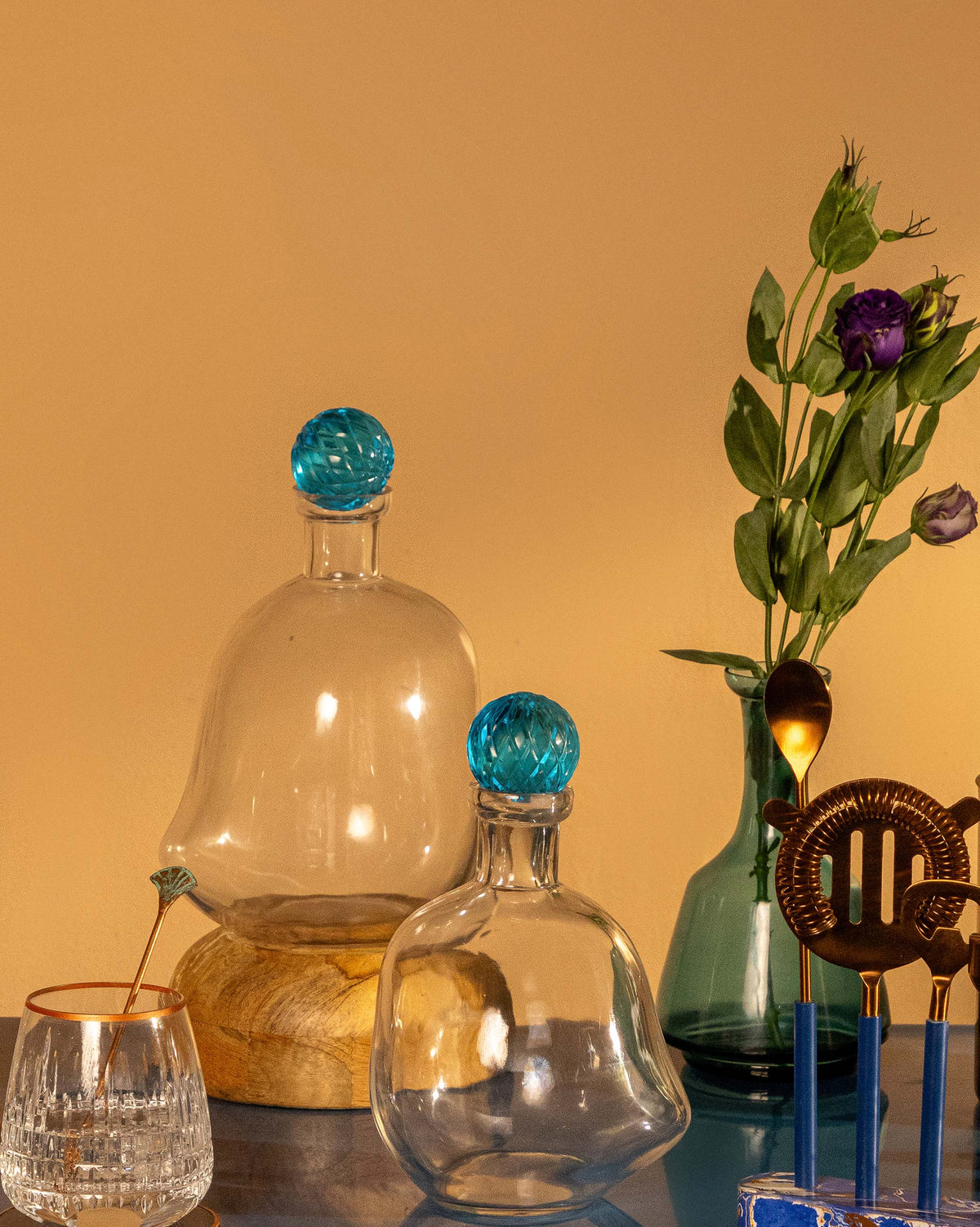 Two Revel Decanters with blue stoppers standing on a shelf.