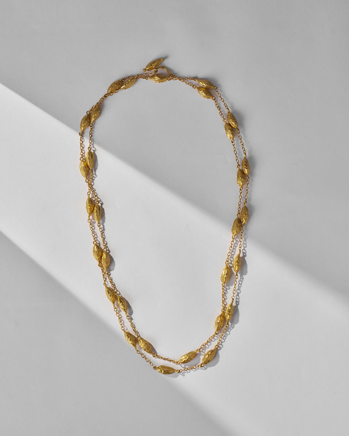 Long gold Shanti Necklace laid flat, showing its beaded double strand.