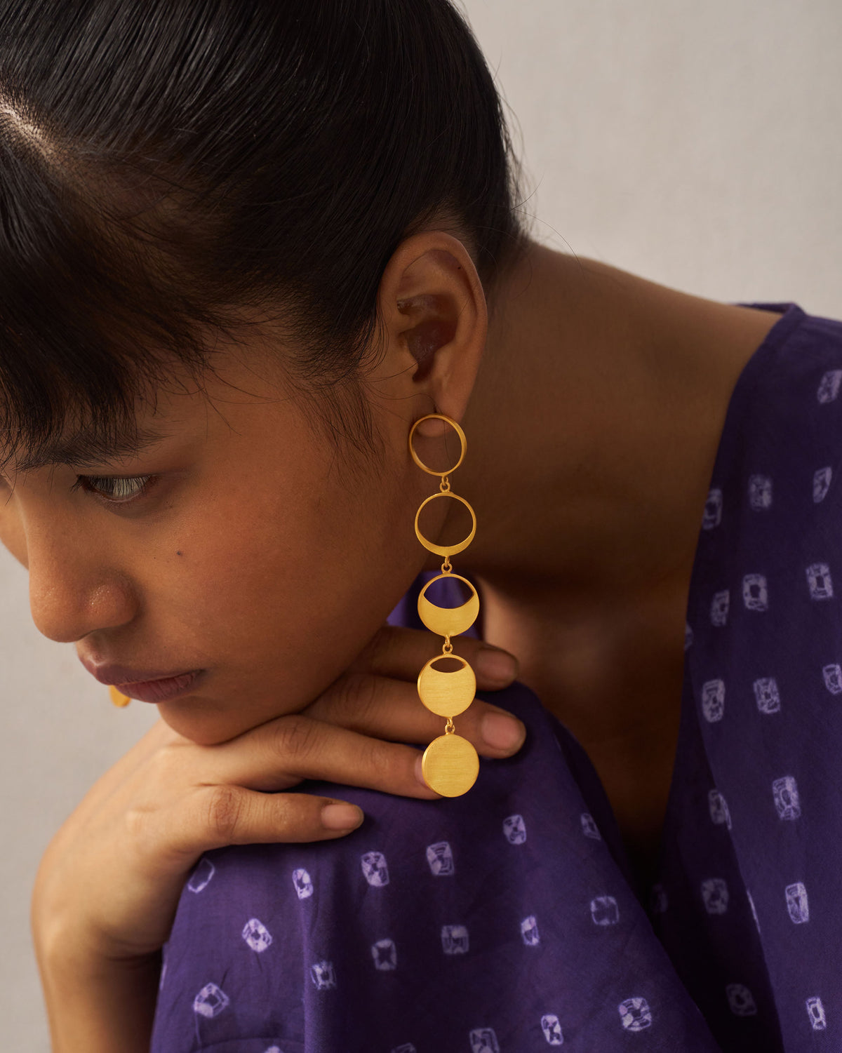 Side profile of gold Waxing Moon danglers showing linked moon phases.
