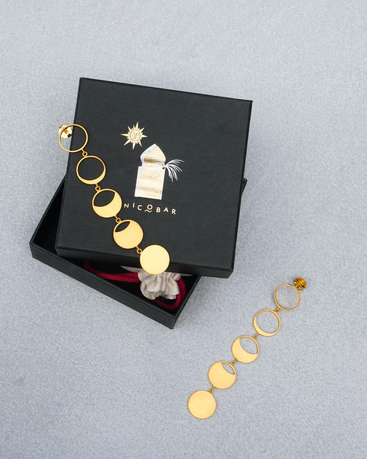 Gold Waxing Moon danglers with moon phases on a black Nicobar gift box.