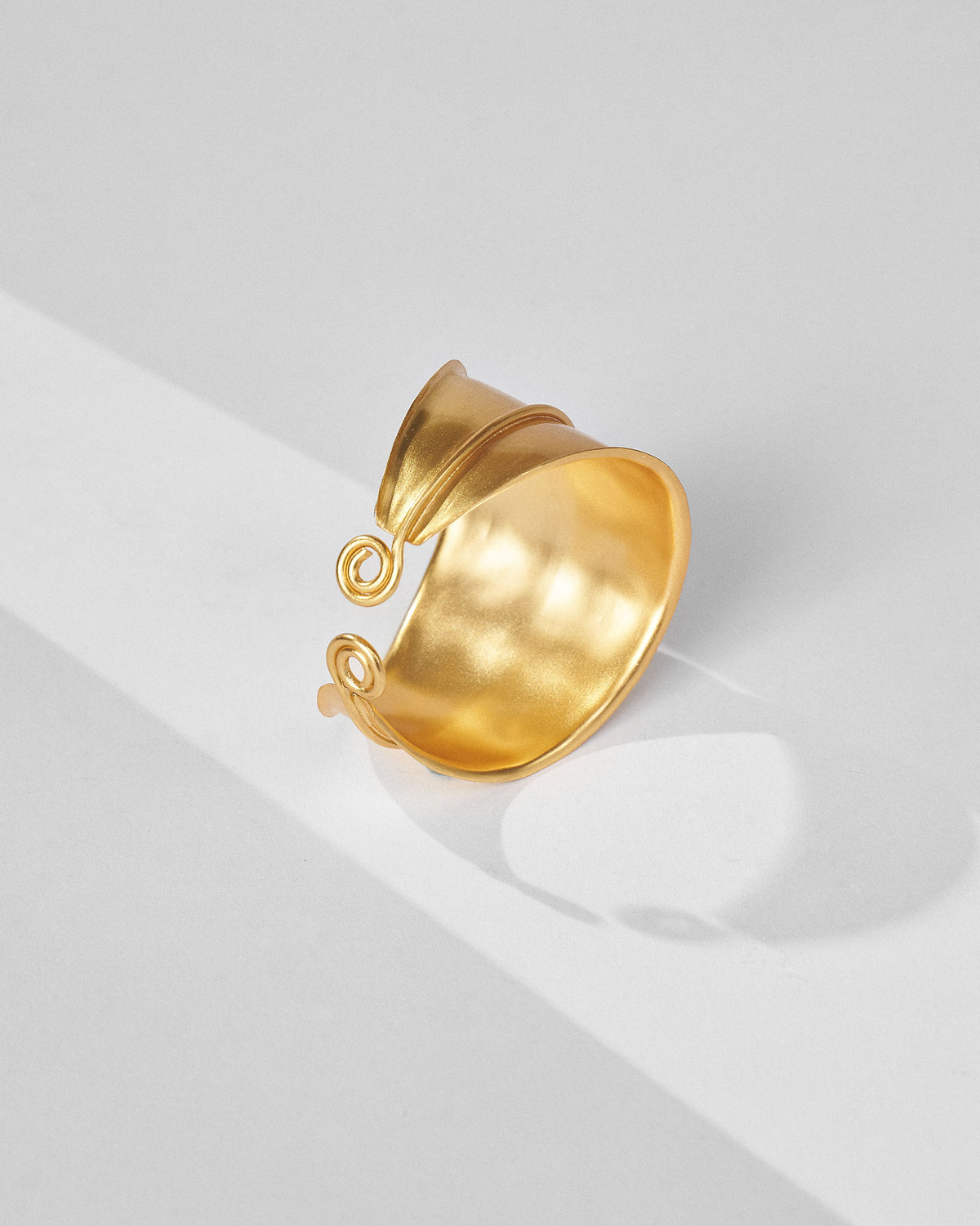 Gold rays cuff open to show its curved band and spiral tips.