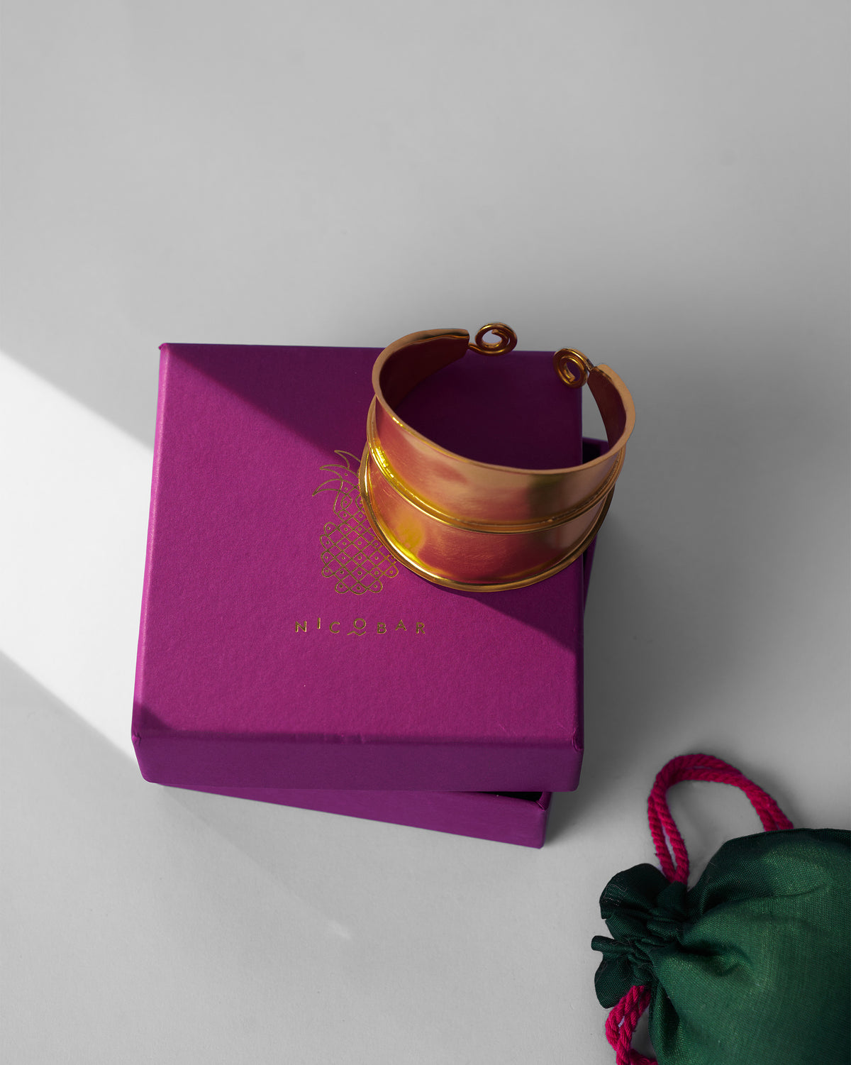 Gold rays cuff beside a Nicobar jewellery box.