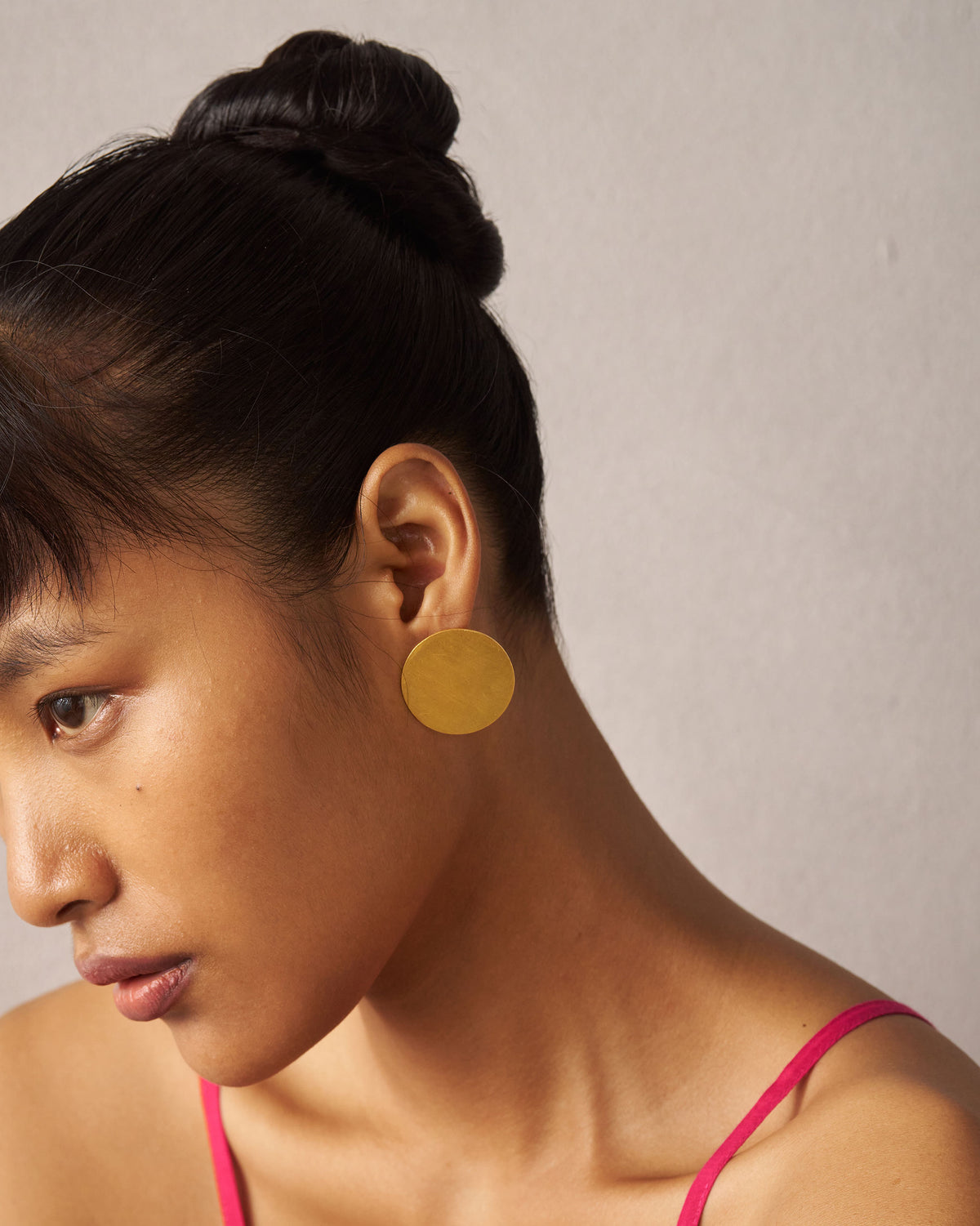Side profile of a gold Sun Moon disc stud on a person.