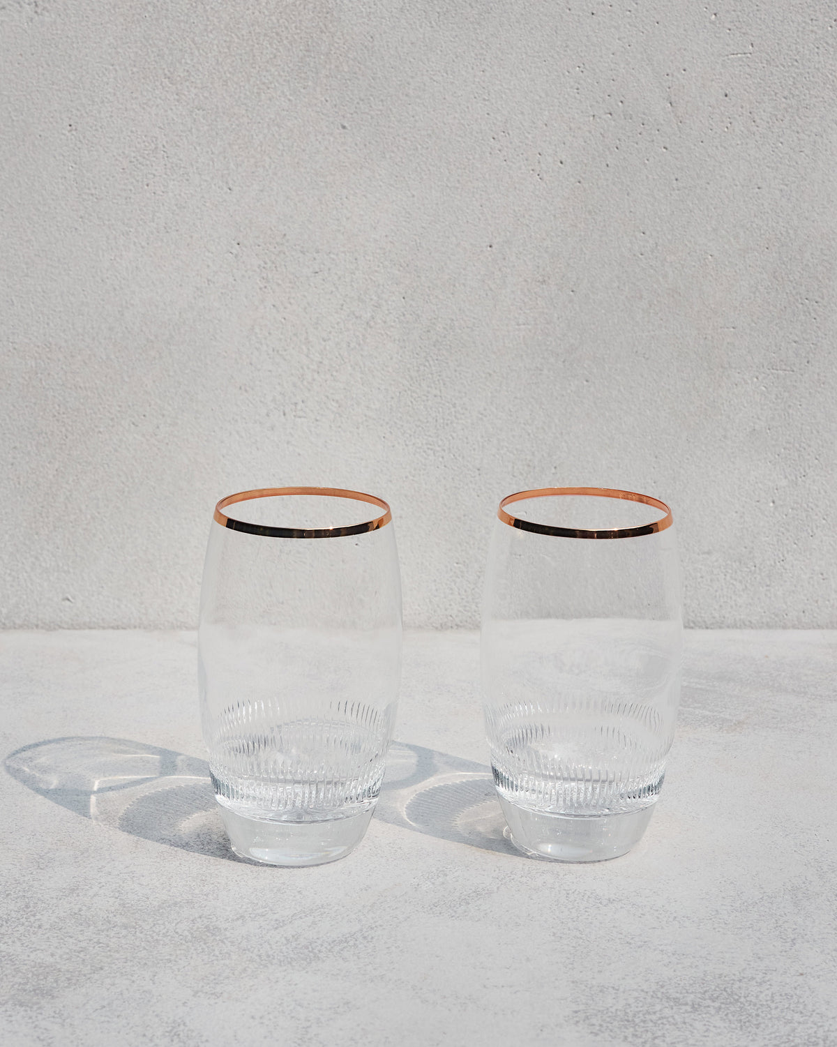Pair of Serena highball glasses with copper rims and ribbed bases.