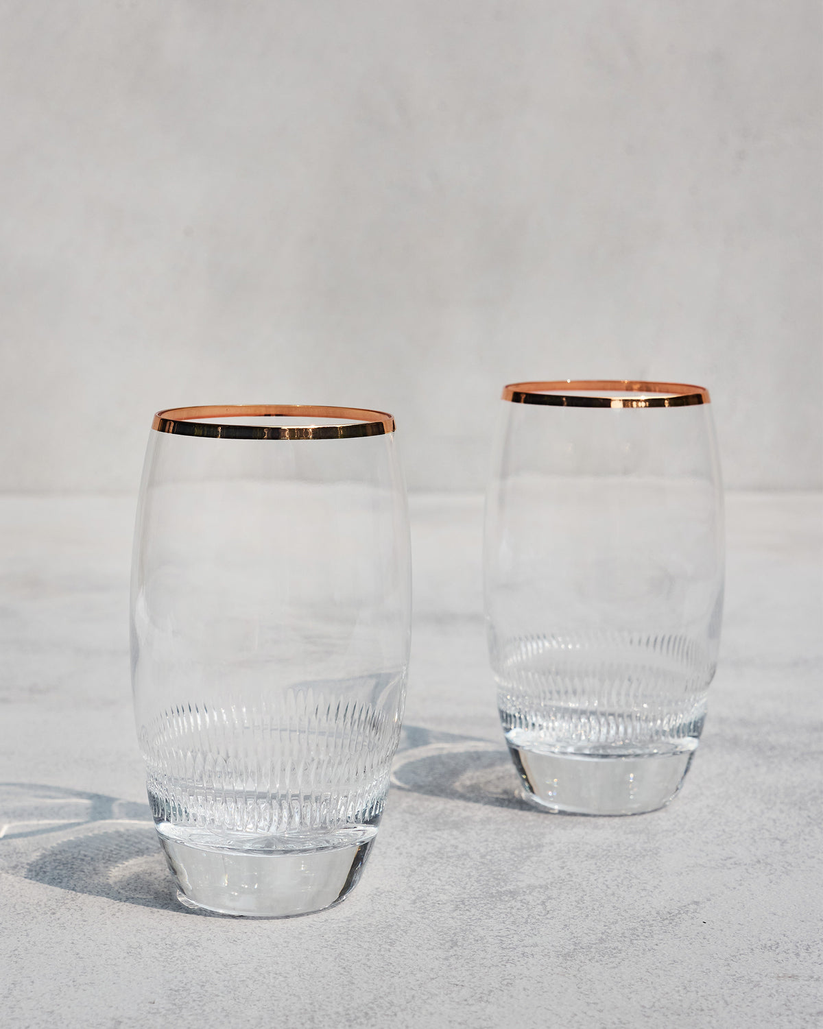 Pair of Serena highball glasses showing their curved copper-rimmed silhouette.