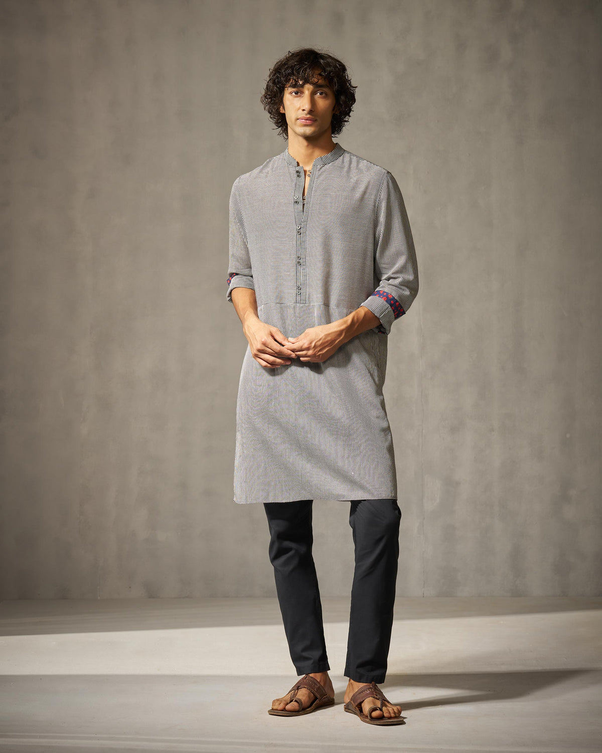 Person wearing a black and ivory striped Revel Kurta with patterned cuff lining.