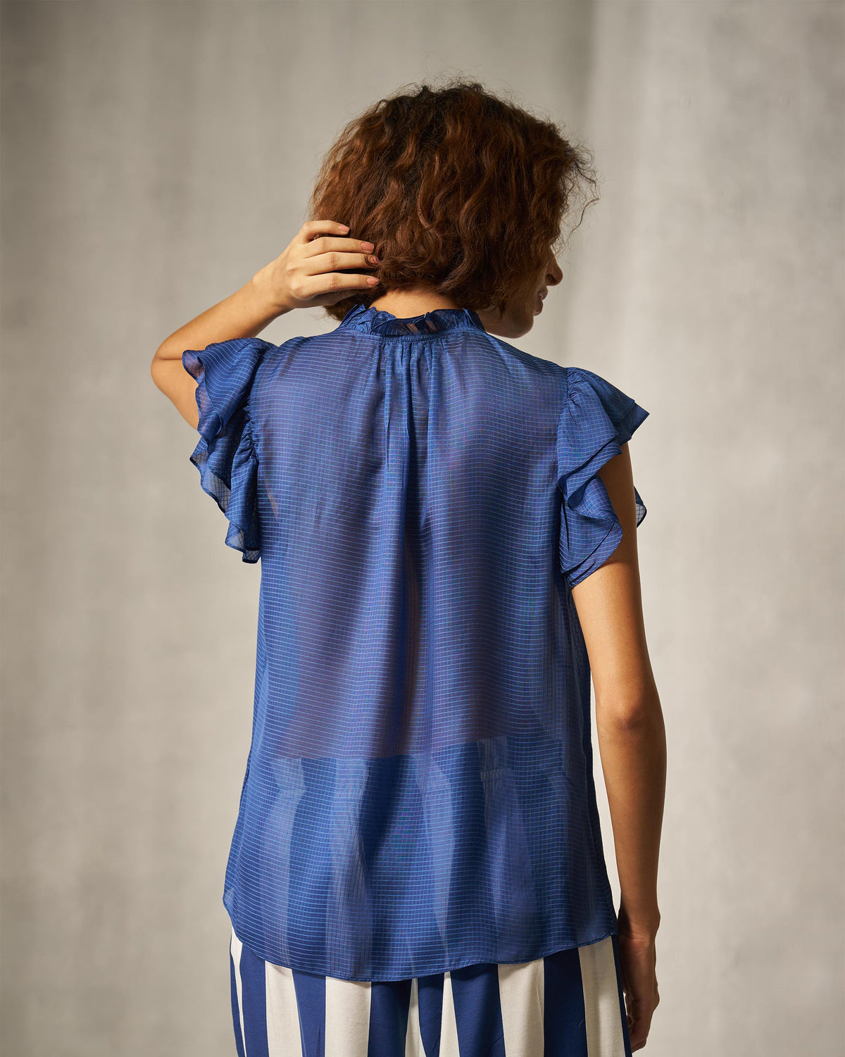 Back of a blue check shirt with layered ruffle sleeves.