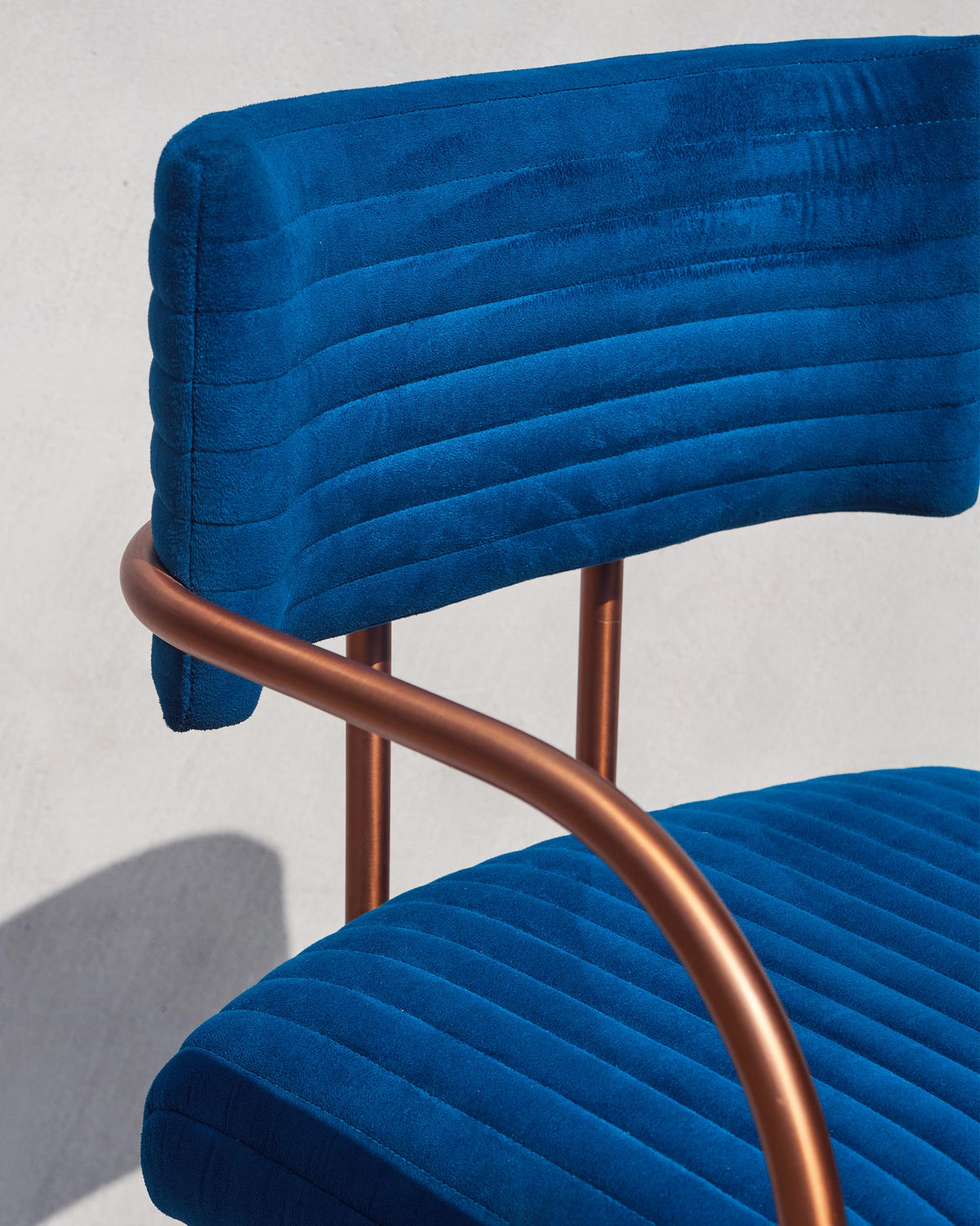 Close-up of a Contours of Time high chair showing blue velvet and copper arms.