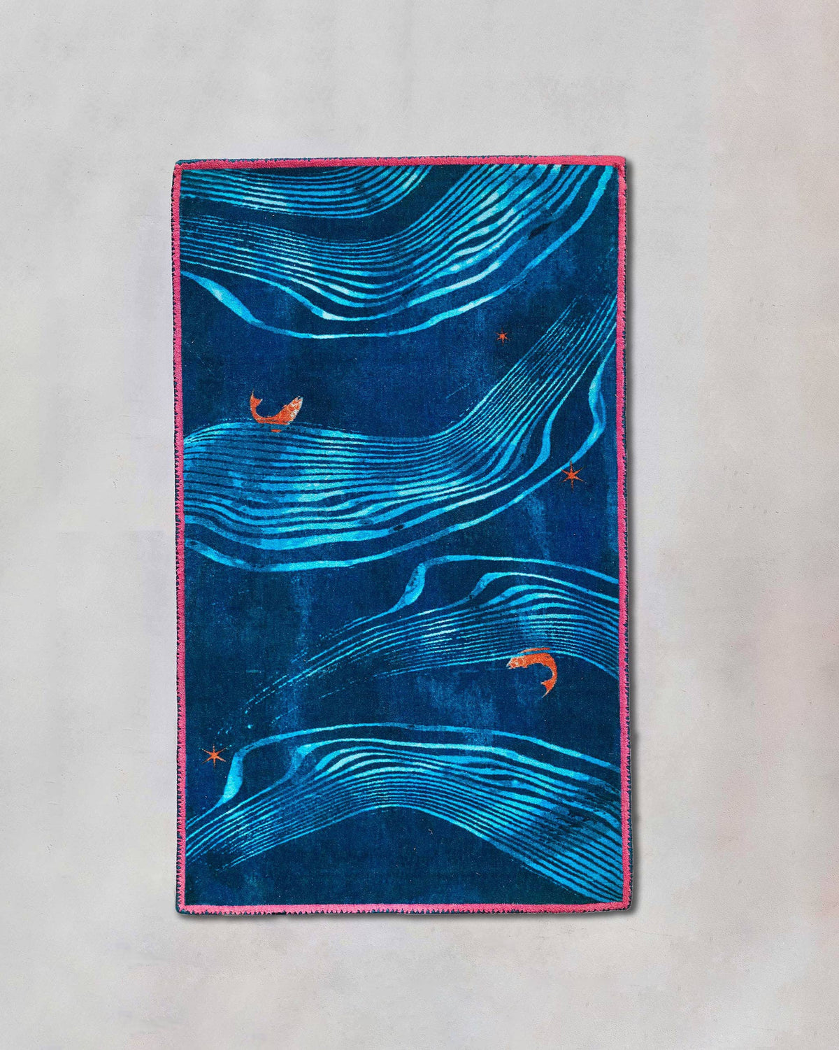Pacific rug with blue wave lines and a pink border, laid flat.
