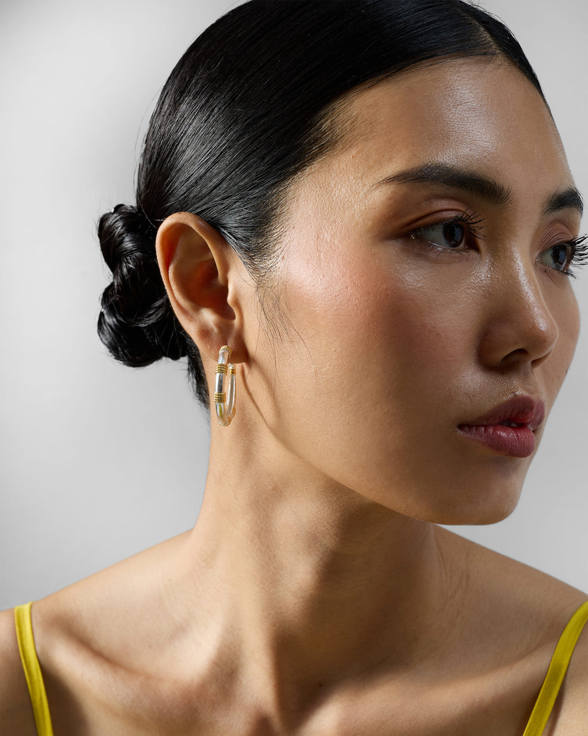 Person wearing a small silver and gold dhoop chaon hoop.