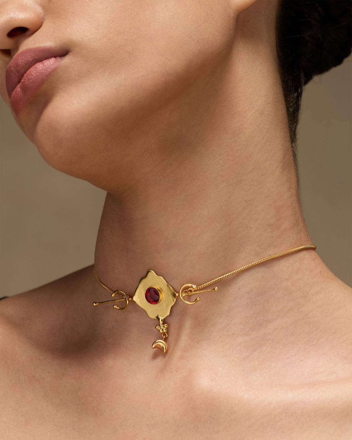 Gold Berber necklace with a red glass pendant and crescent charm worn at the neck.