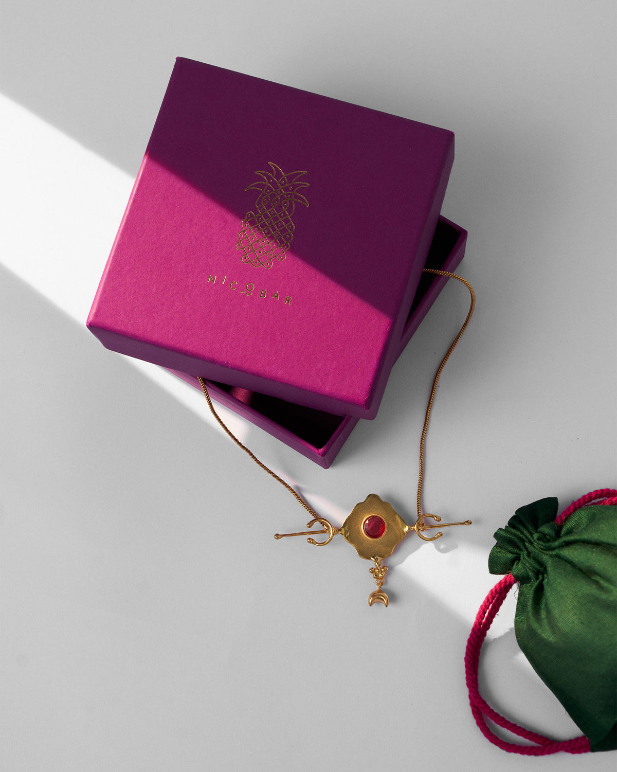 Gold Berber necklace with a magenta Nicobar gift box and green pouch.