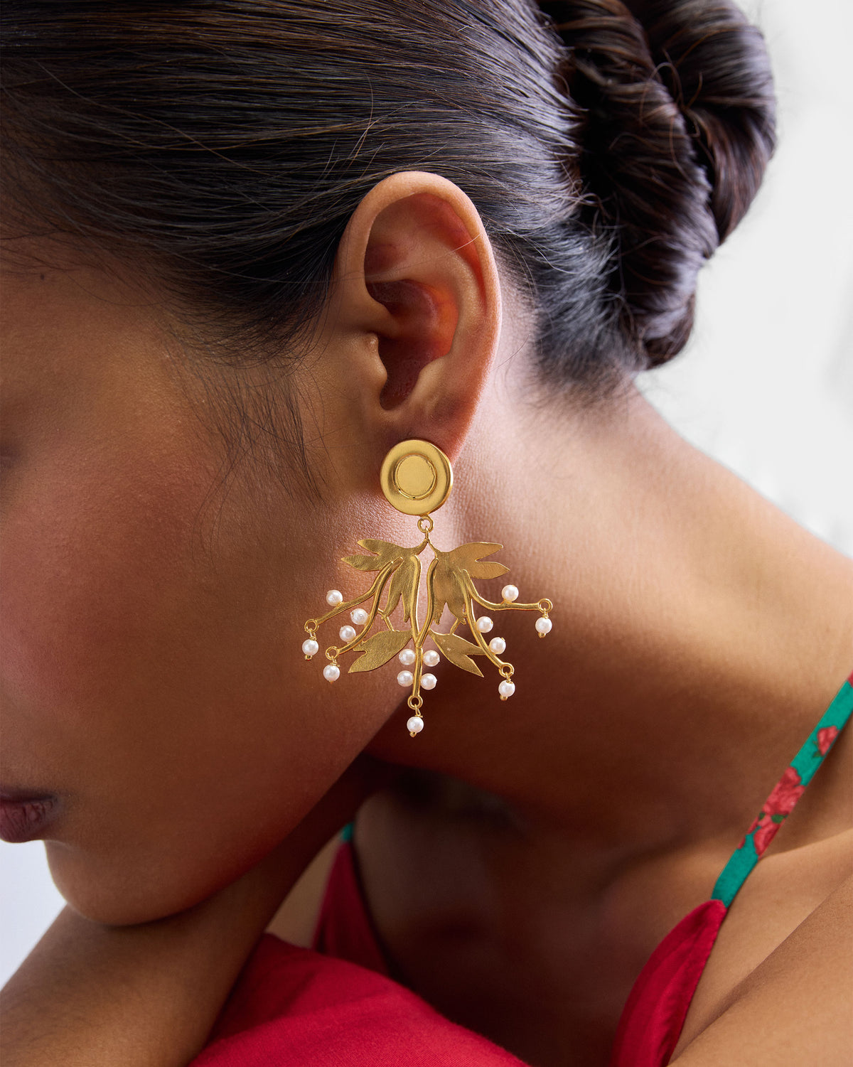 Close-up of Anaar Cluster Earrings worn, showing gold leaves and pearl drops.
