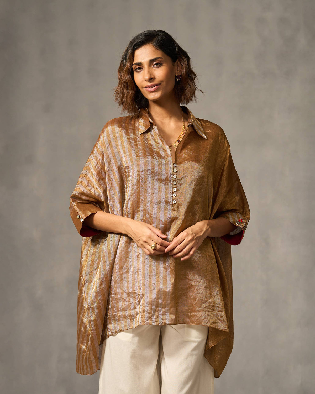 Person wearing a gold and silver Hala tunic with a collared placket.