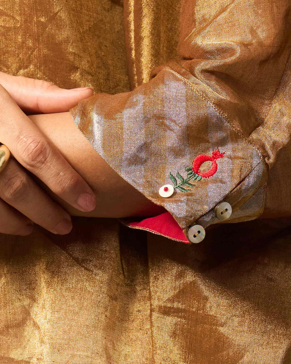 Close-up of anar embroidery on the cuff of a gold Hala tunic.