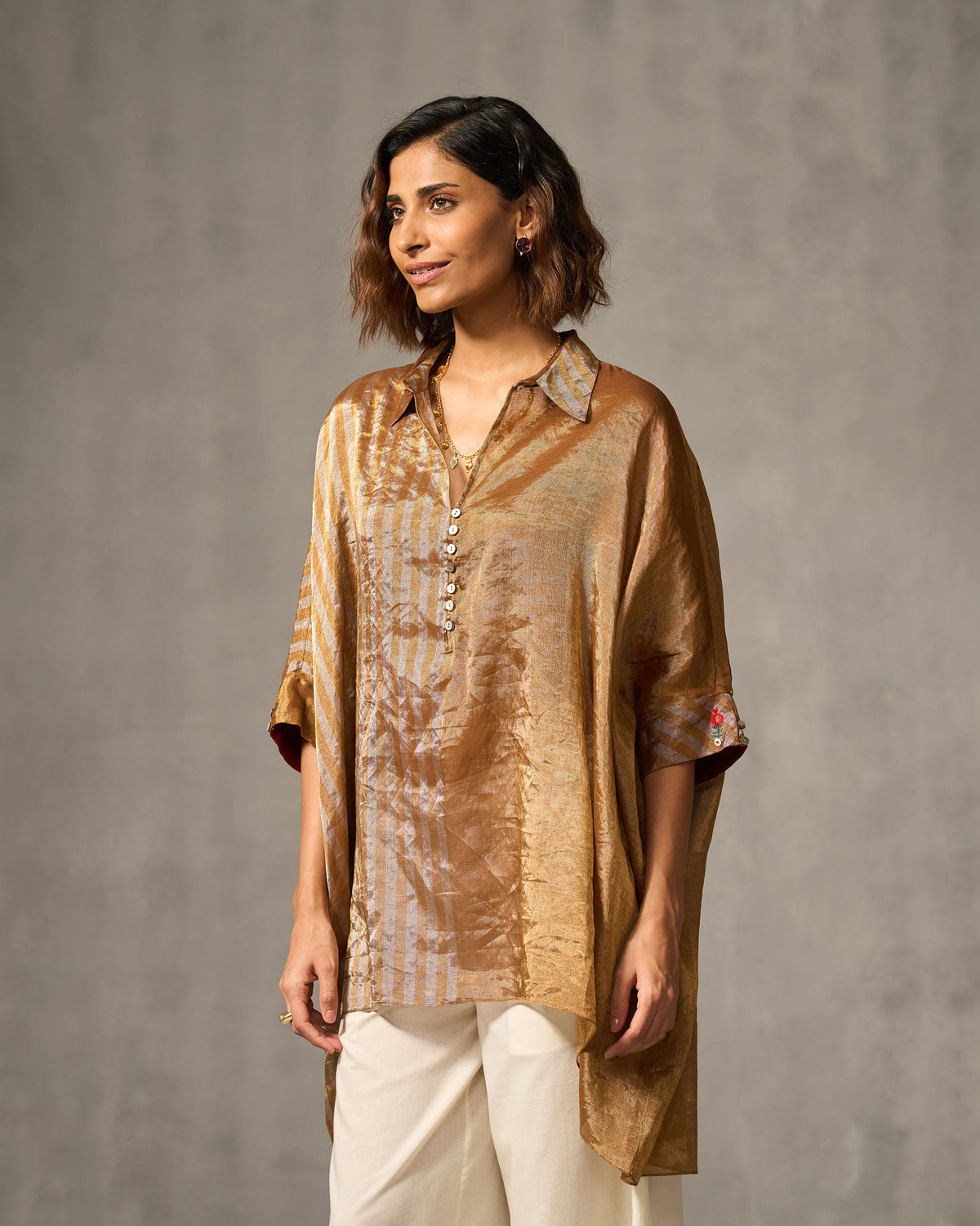Person wearing an oversized gold and silver Hala tunic.