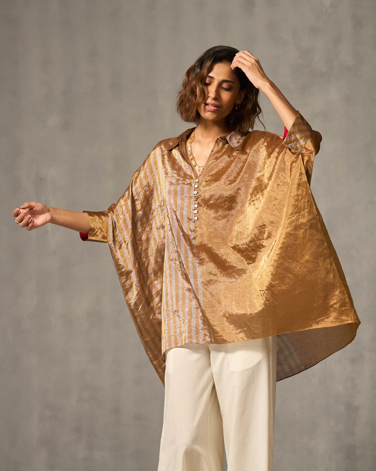 Person wearing a metallic Hala tunic with wide sleeves and a high-low hem.