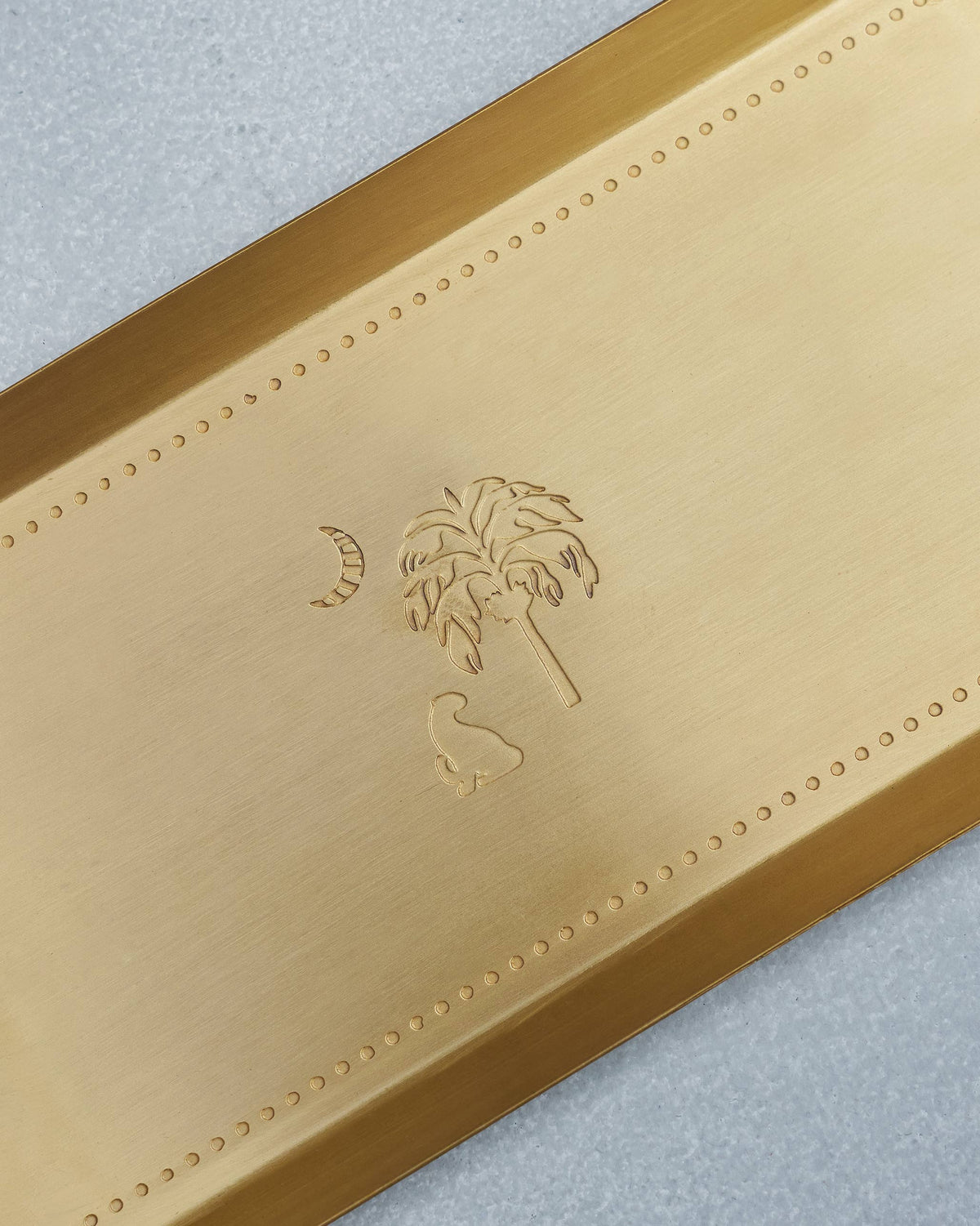 Close-up of Sahara tray engraving with a palm, crescent moon, and animal.