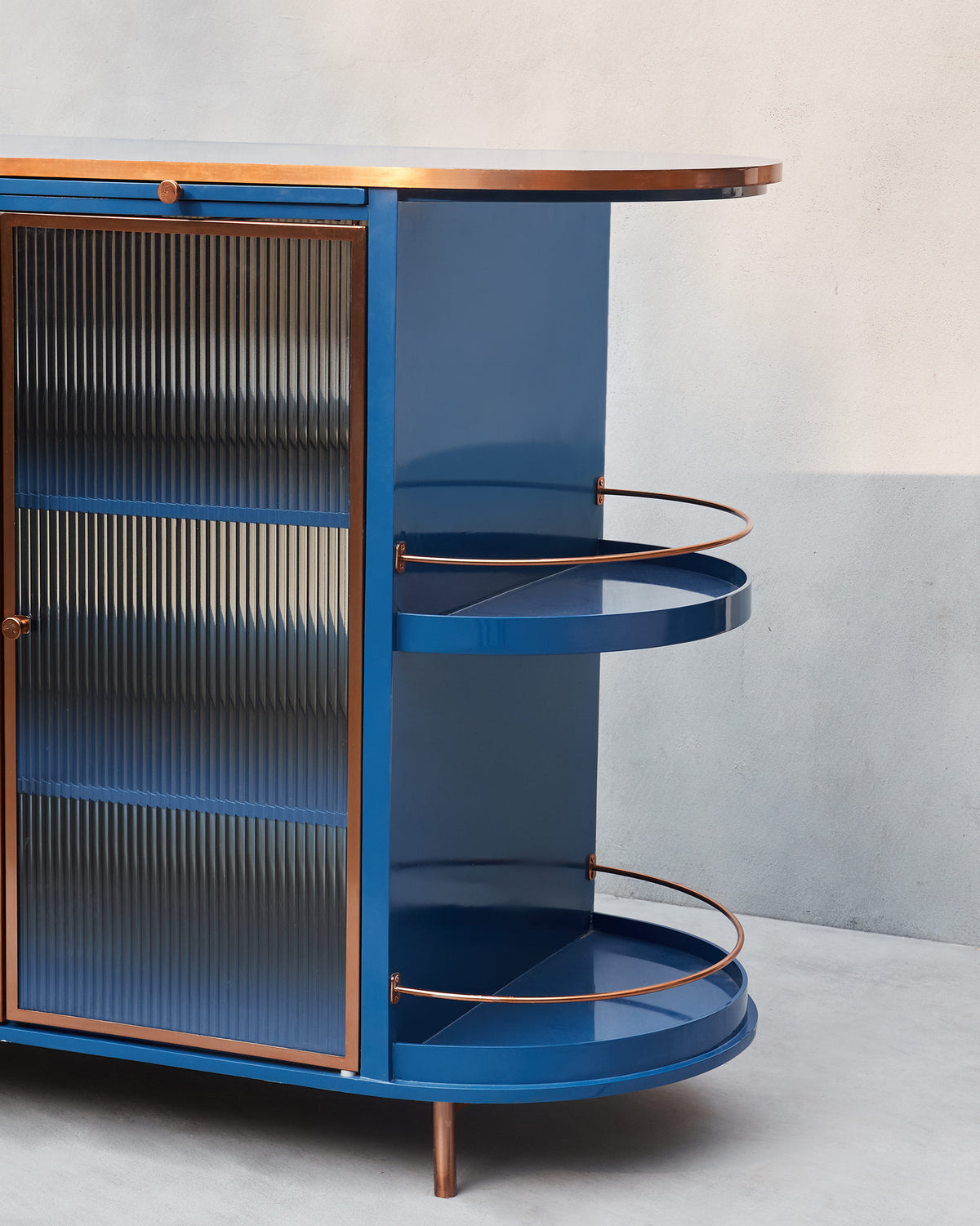 Angled Contours of Time cabinet showing fluted glass and copper-railed shelves.