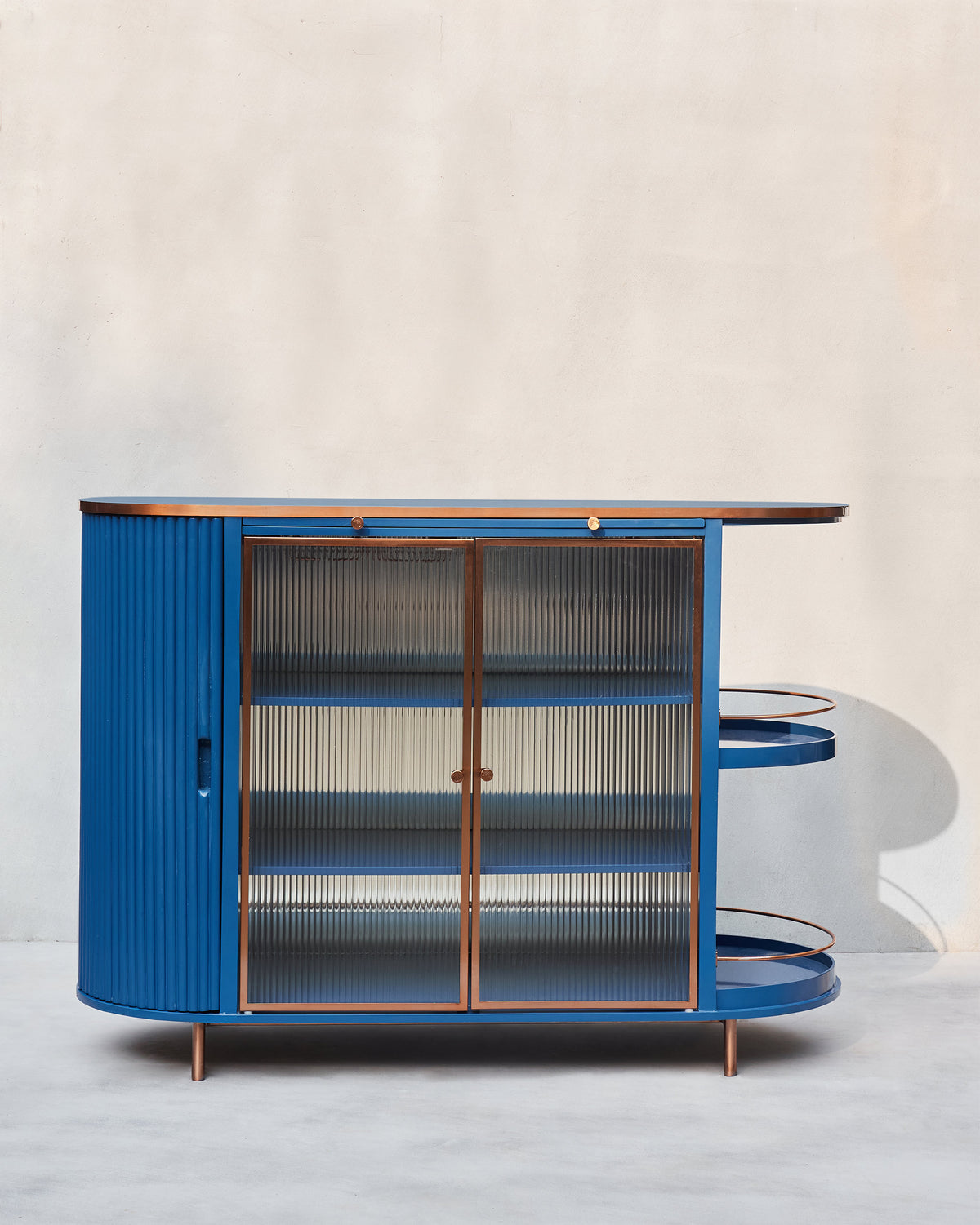 Front view of the blue Contours of Time cabinet with glass doors and open shelves.