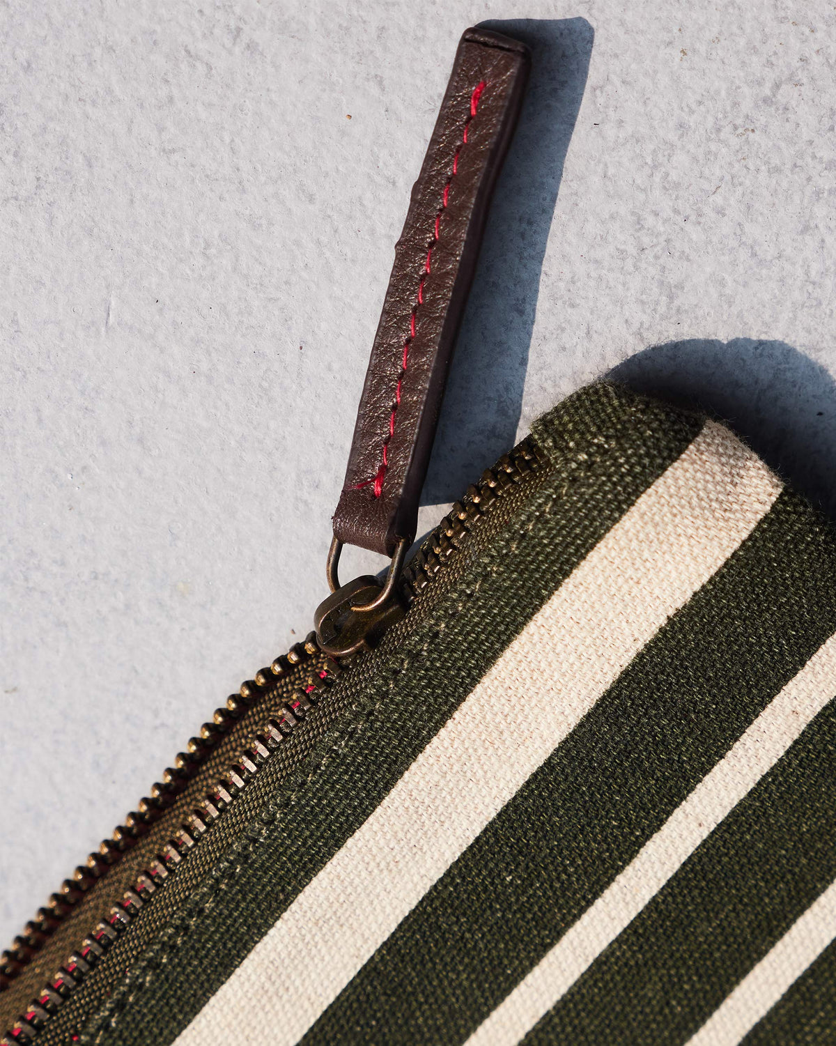 Close-up of the Alphabet B Pouch with its leather zip pull and red stitching.