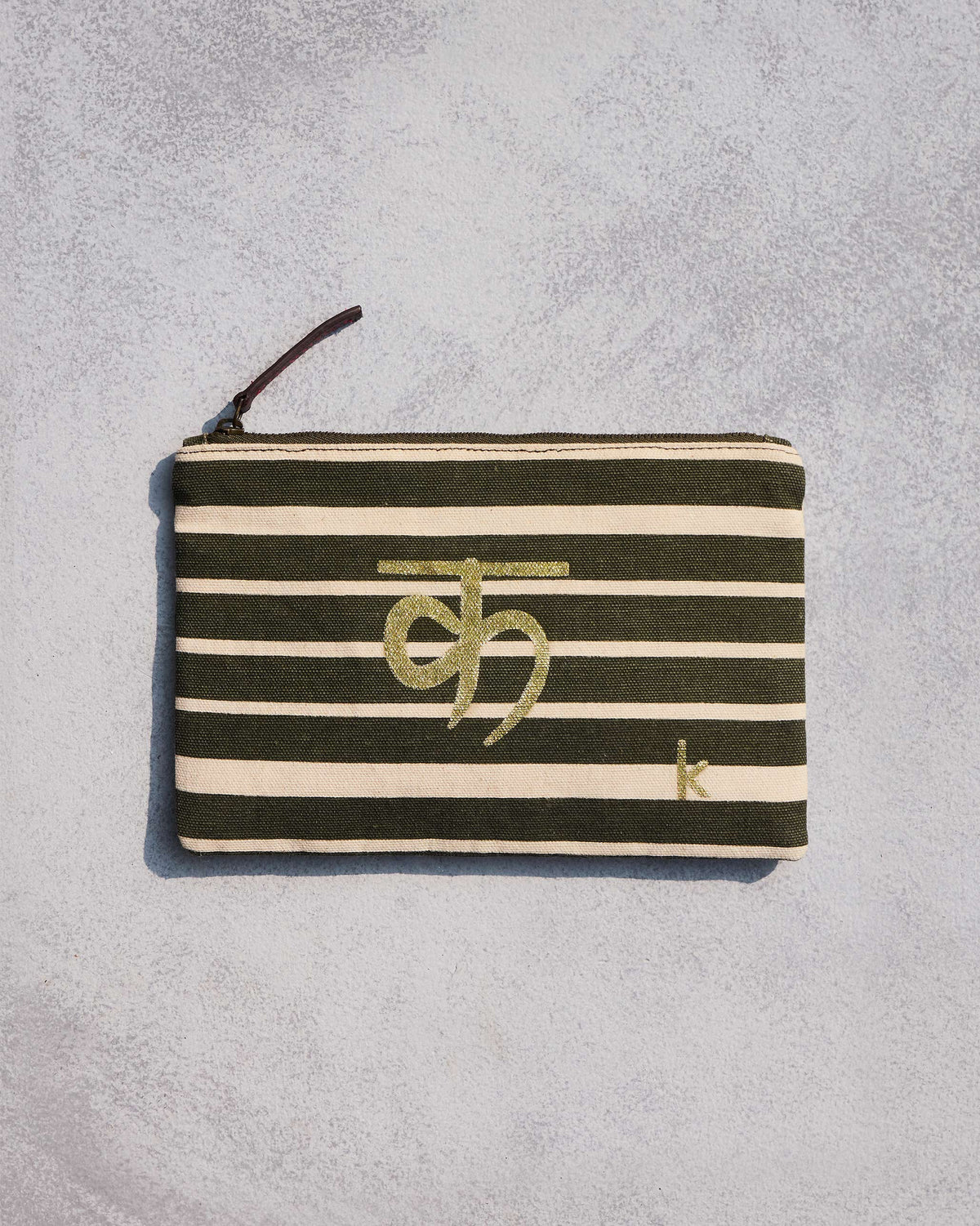 Alphabet K Pouch in olive and cream stripes with a gold script letter.