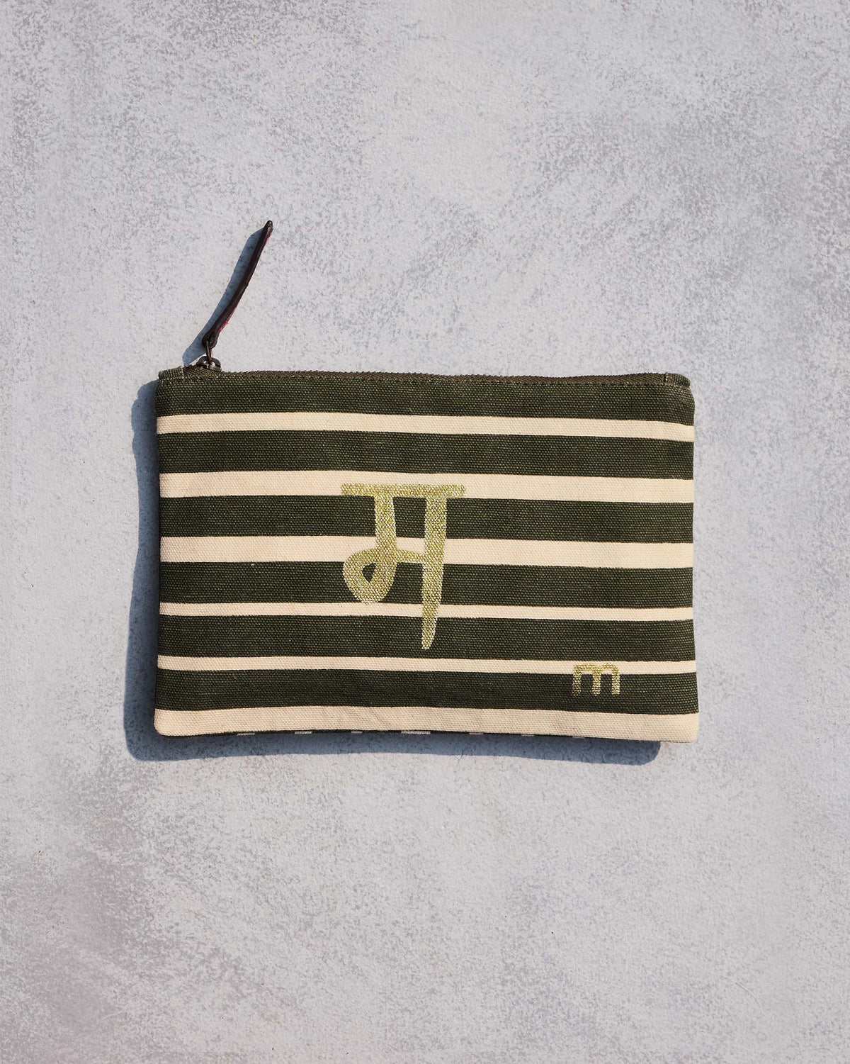 Alphabet M Pouch in olive and cream stripes with a gold script letter.