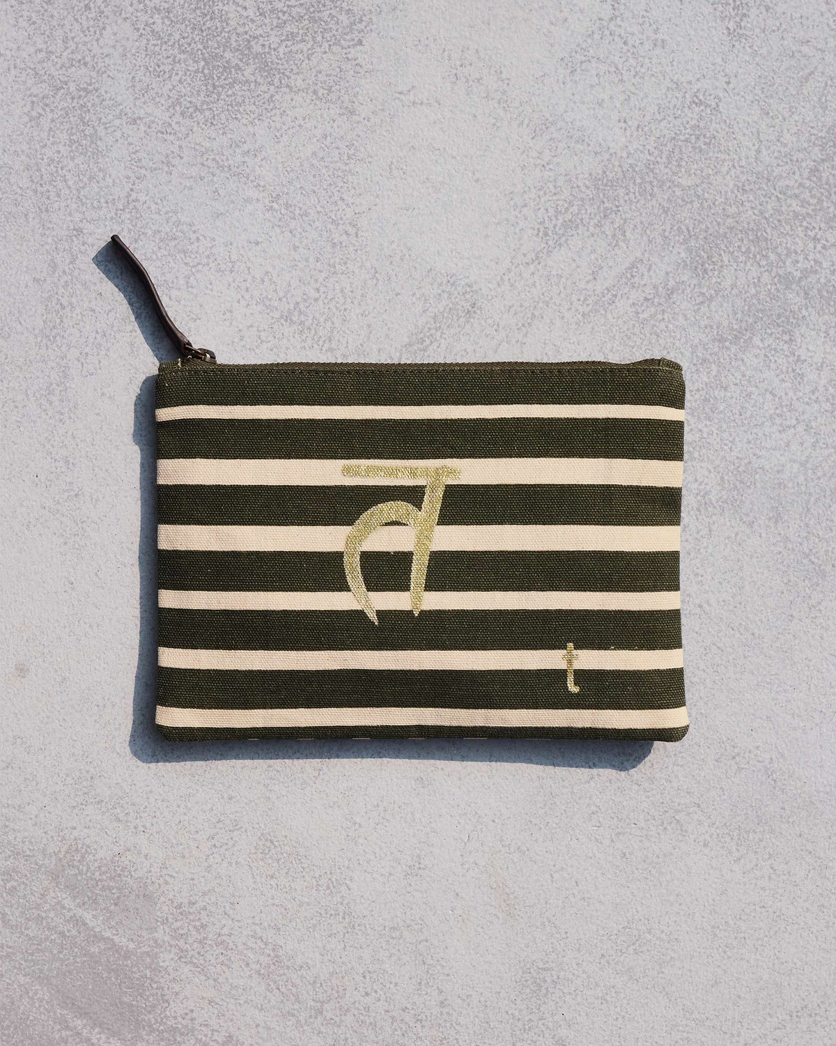 Alphabet T Pouch in olive and cream stripes with a gold script letter.