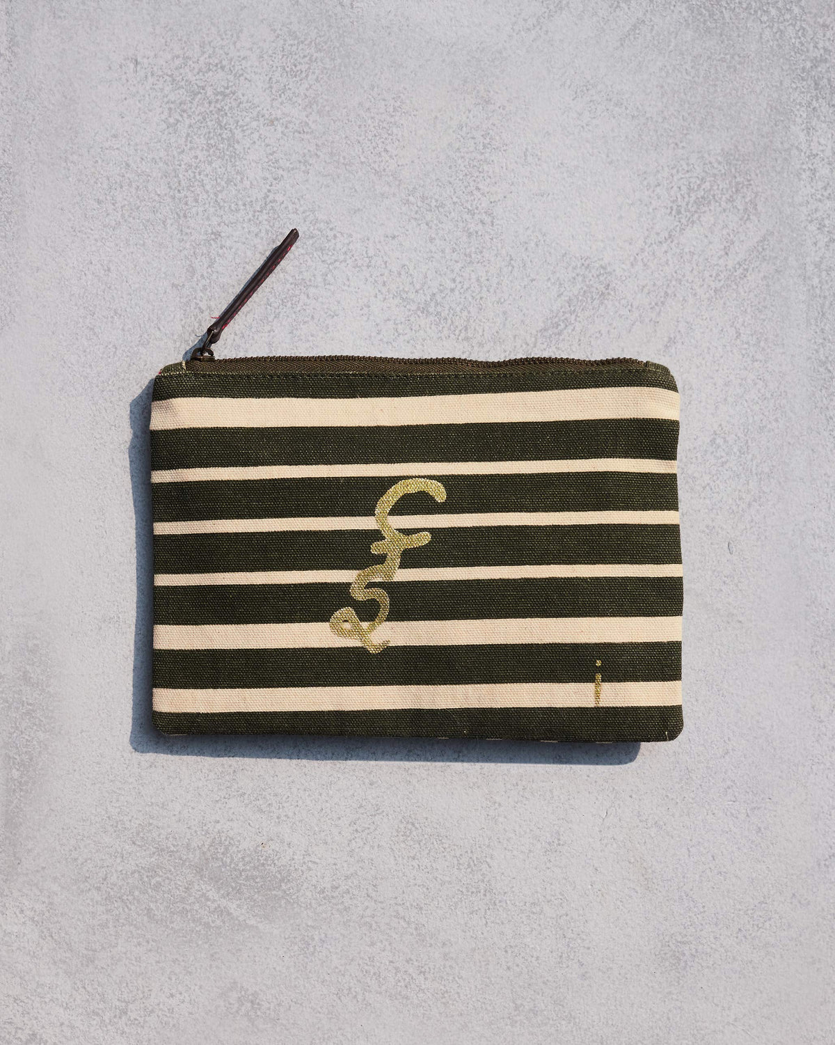 Alphabet I Pouch in olive and cream stripes with a gold script letter.