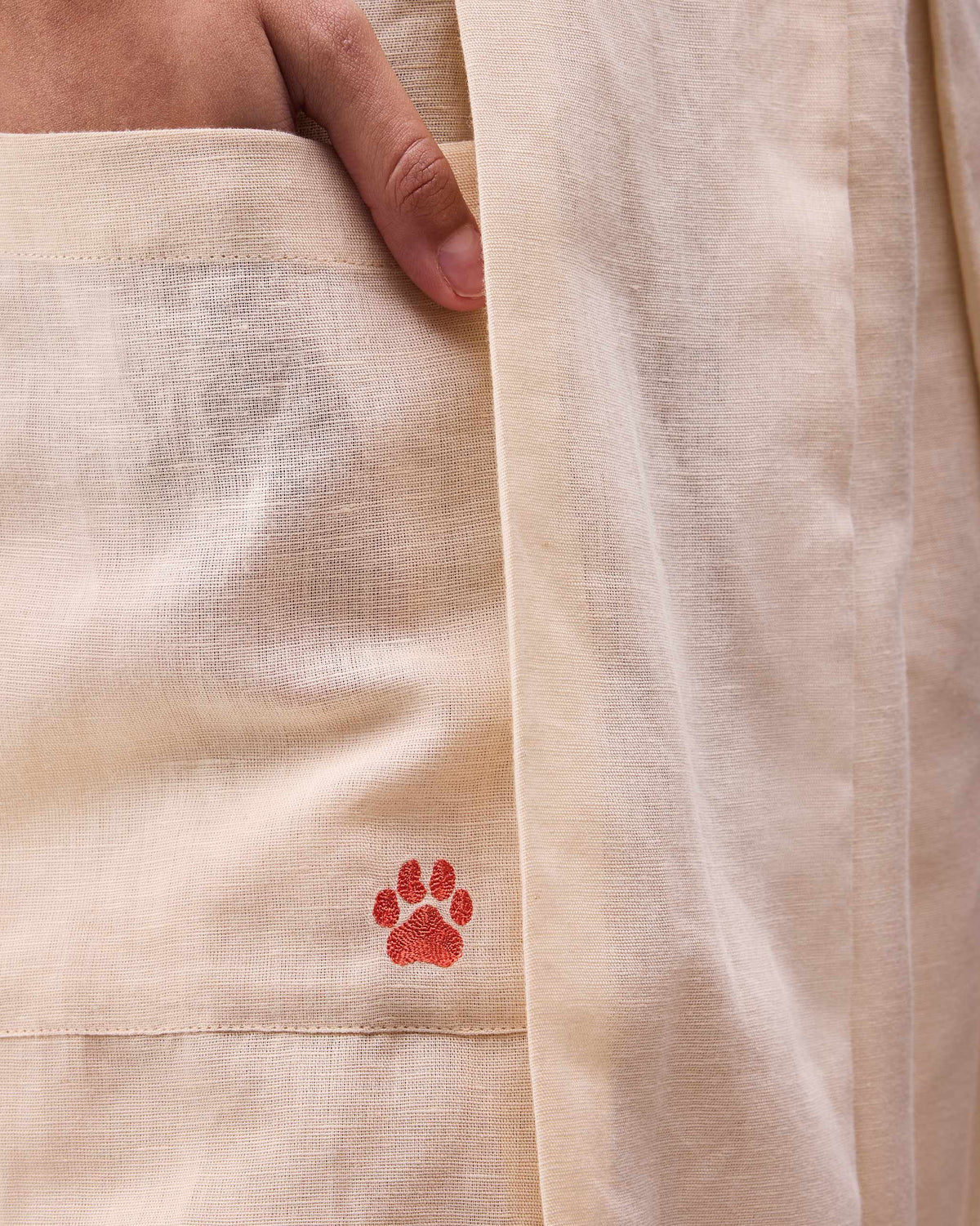 Close-up of a rust paw on a beige Pocket skort pocket.