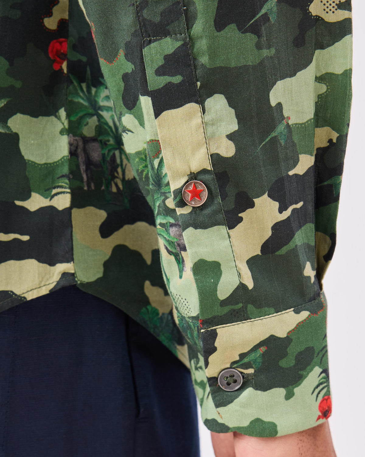 Close-up of a Hakuna shirt sleeve with a red star button on the placket.