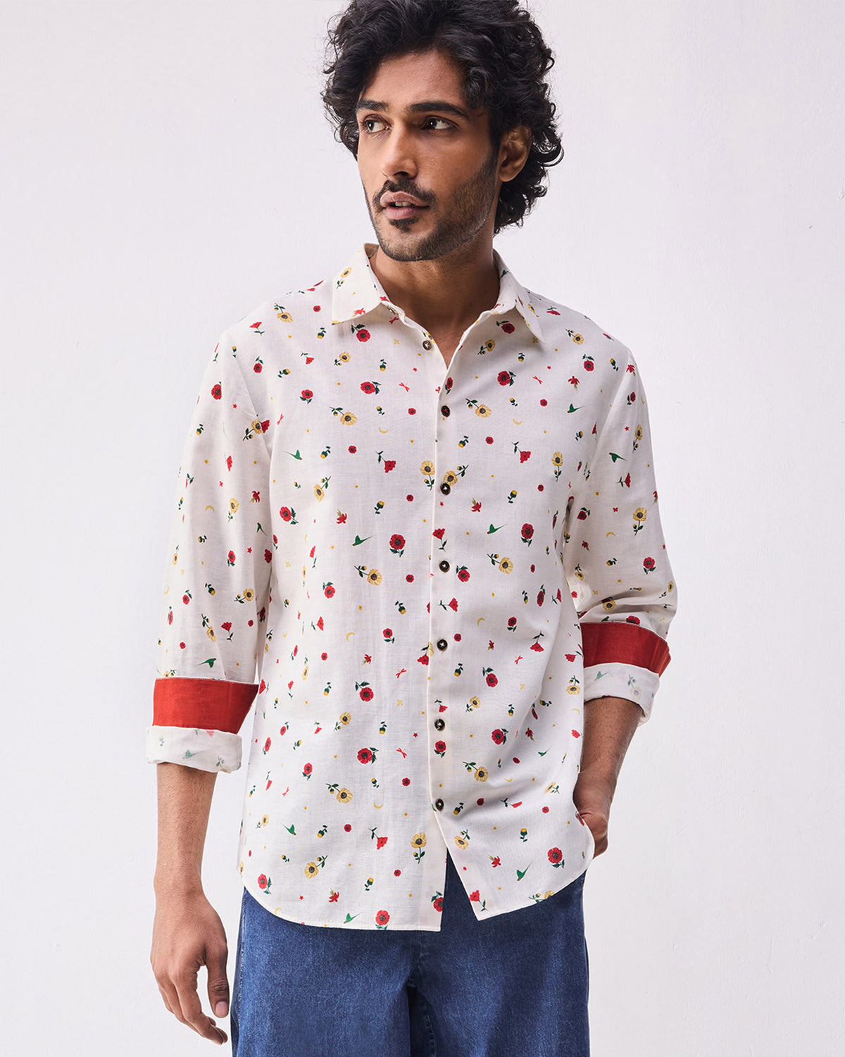 Person wearing an ivory Catamaran shirt with a small floral print and red cuff lining.