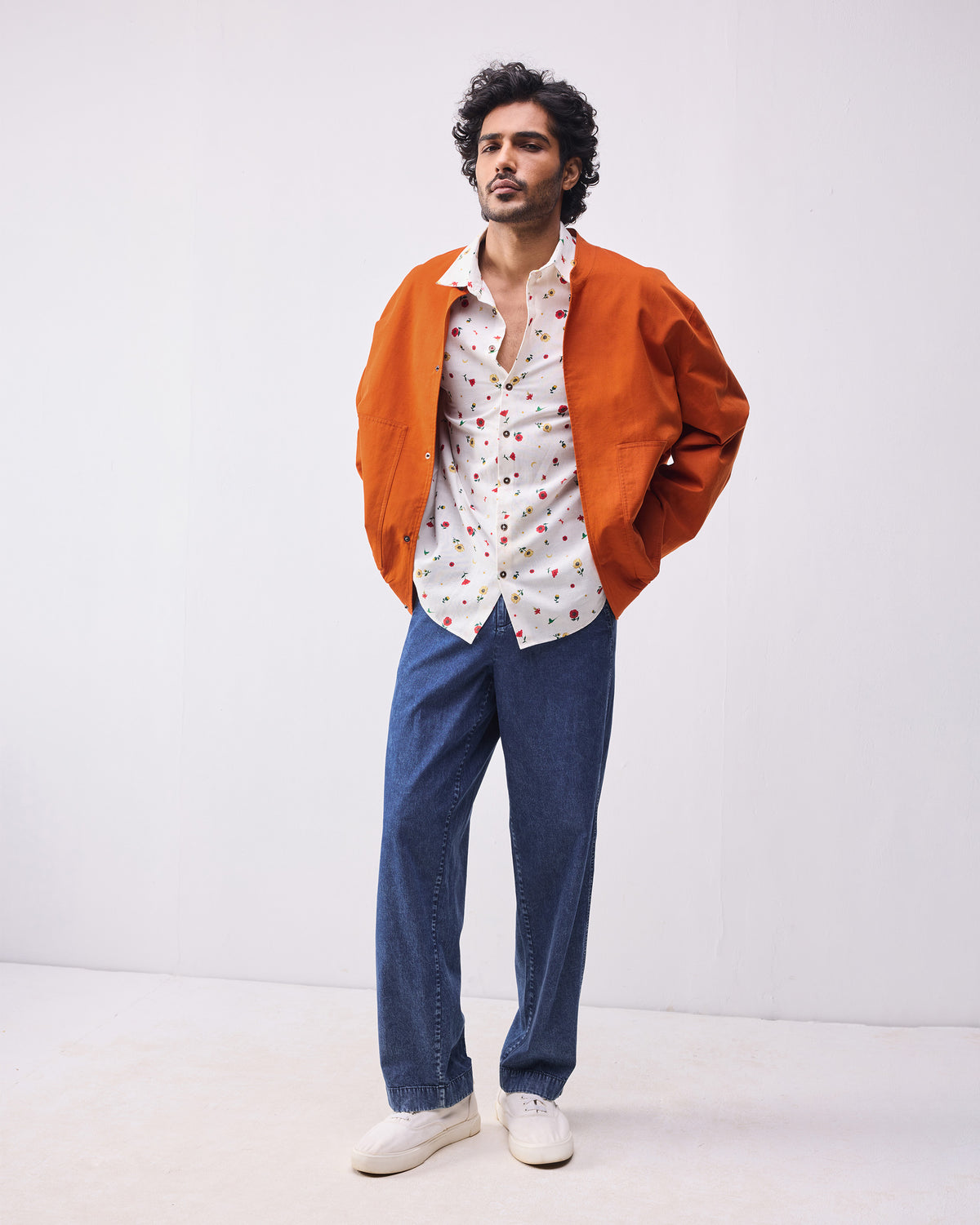 Person wearing a rust Safar bomber open over a printed shirt.
