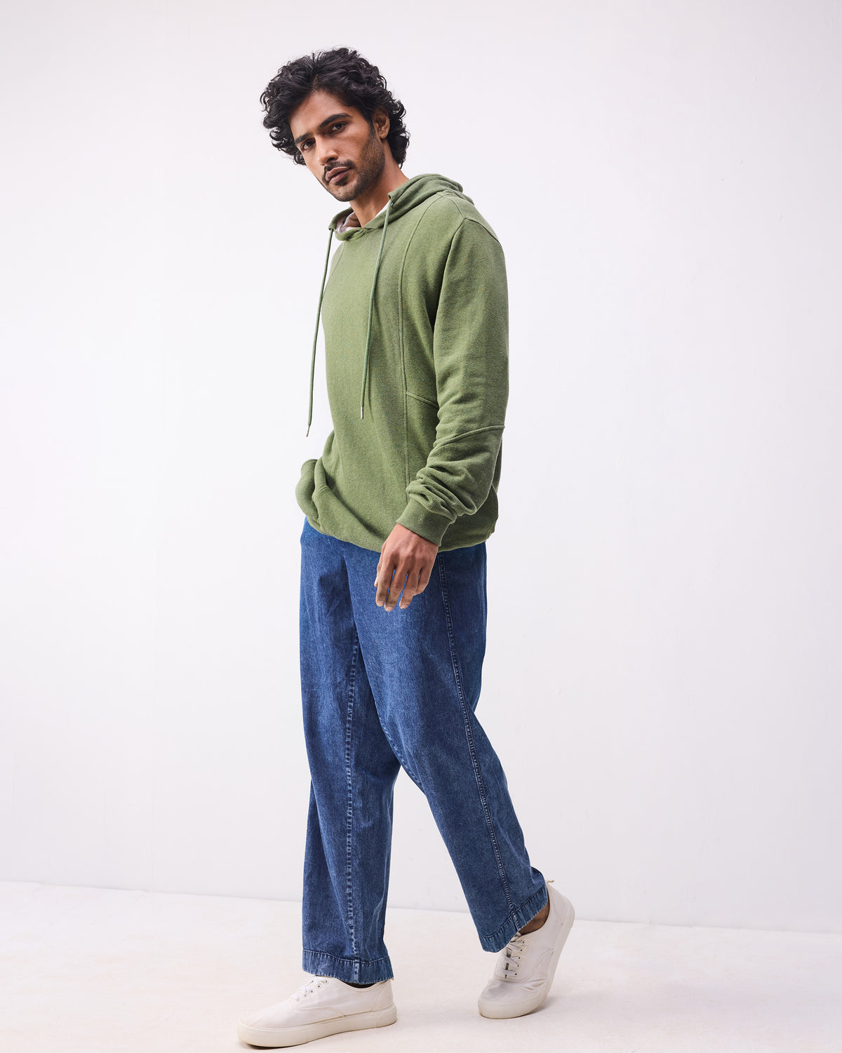 Person wearing an olive green Urban Sweatshirt hoodie with jeans.