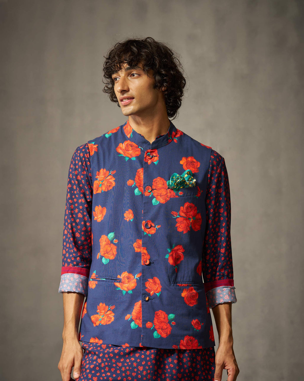 Person wearing a navy rose-print Nehru jacket with a teal pocket square.
