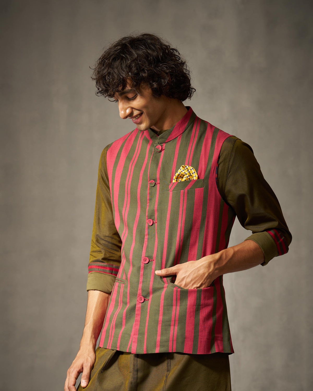 Person wearing a red and oak brown striped Nehru jacket with patch pockets.