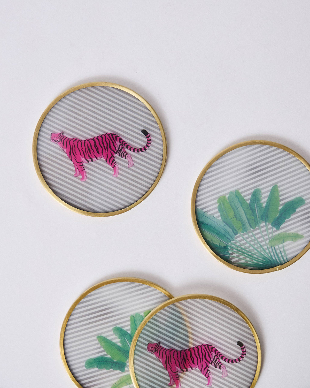 Four Ceylon Trail brass-rim coasters with tiger and leaf prints scattered.
