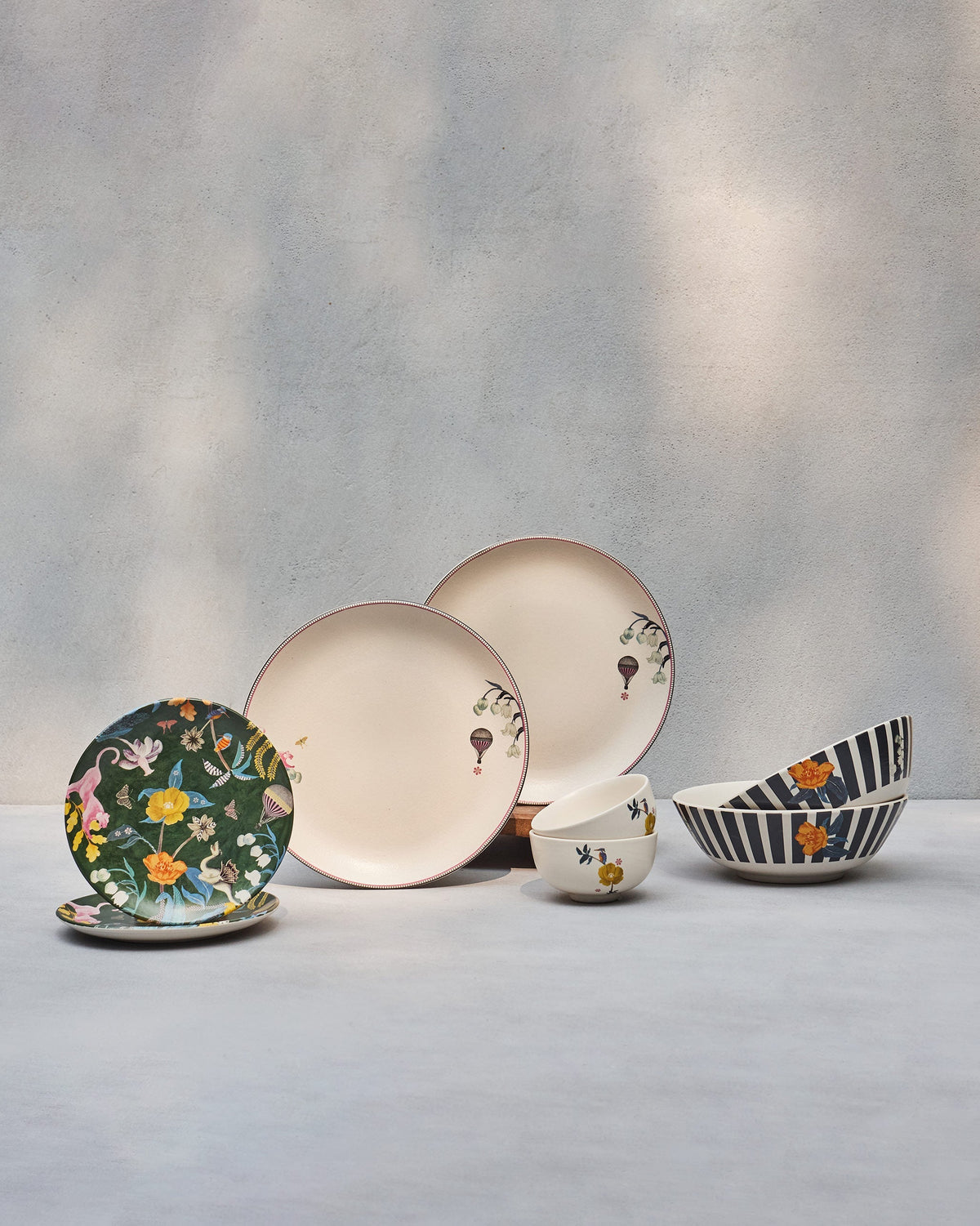 Myra dinner set for two with cream plates, jungle plates, and striped bowls.