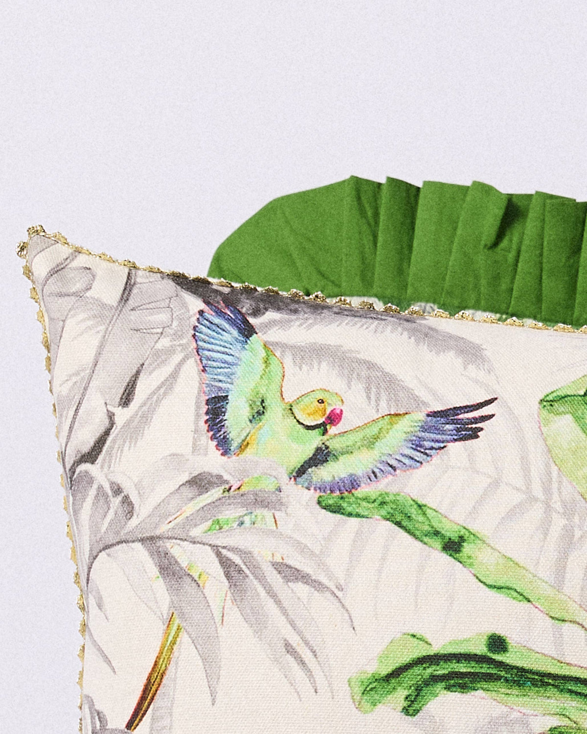 Close-up of a green parrot on a Ceylon Ele cushion with gold trim.
