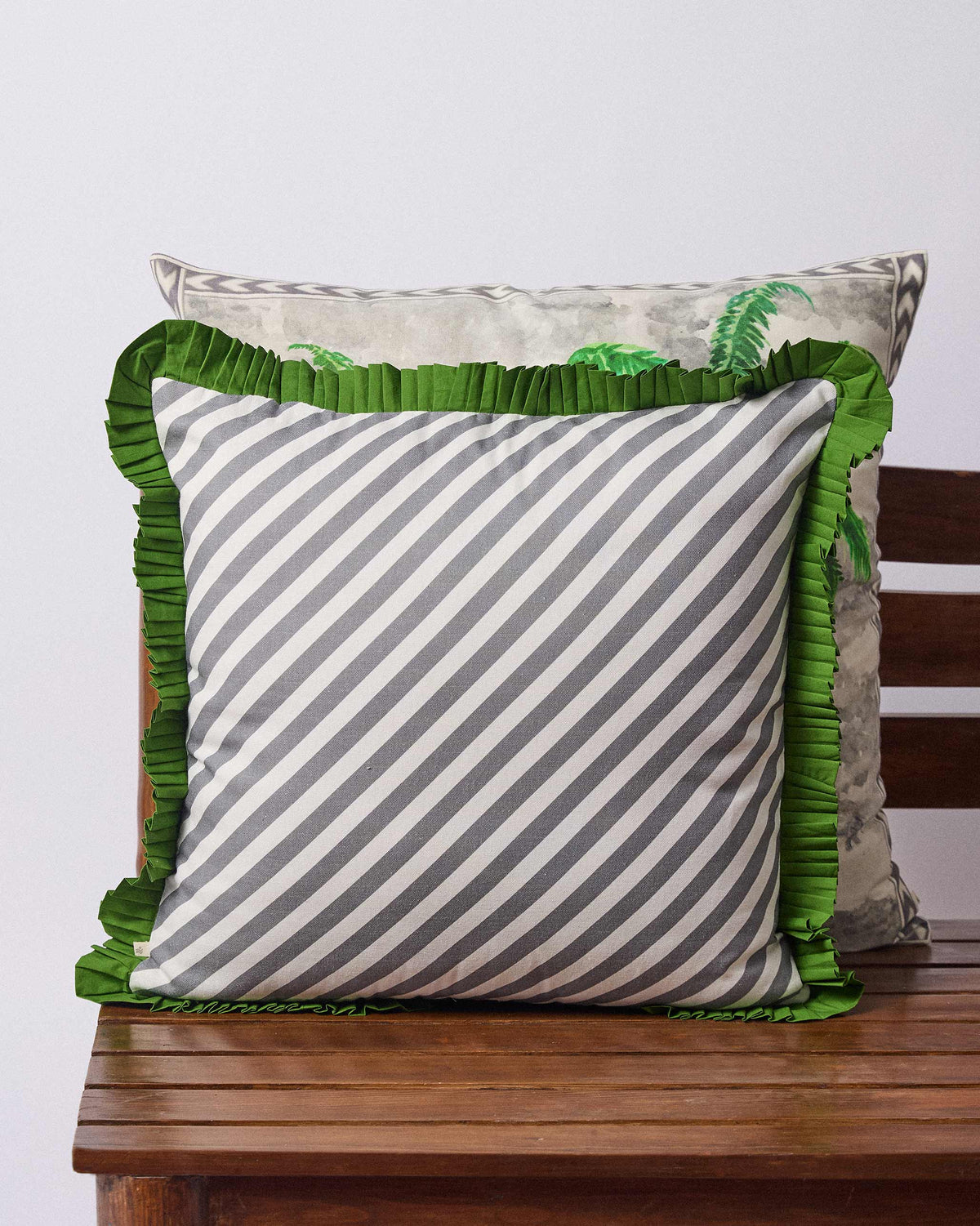 Back of the Palm Trail cushion cover in grey and white stripes with a green ruffle.
