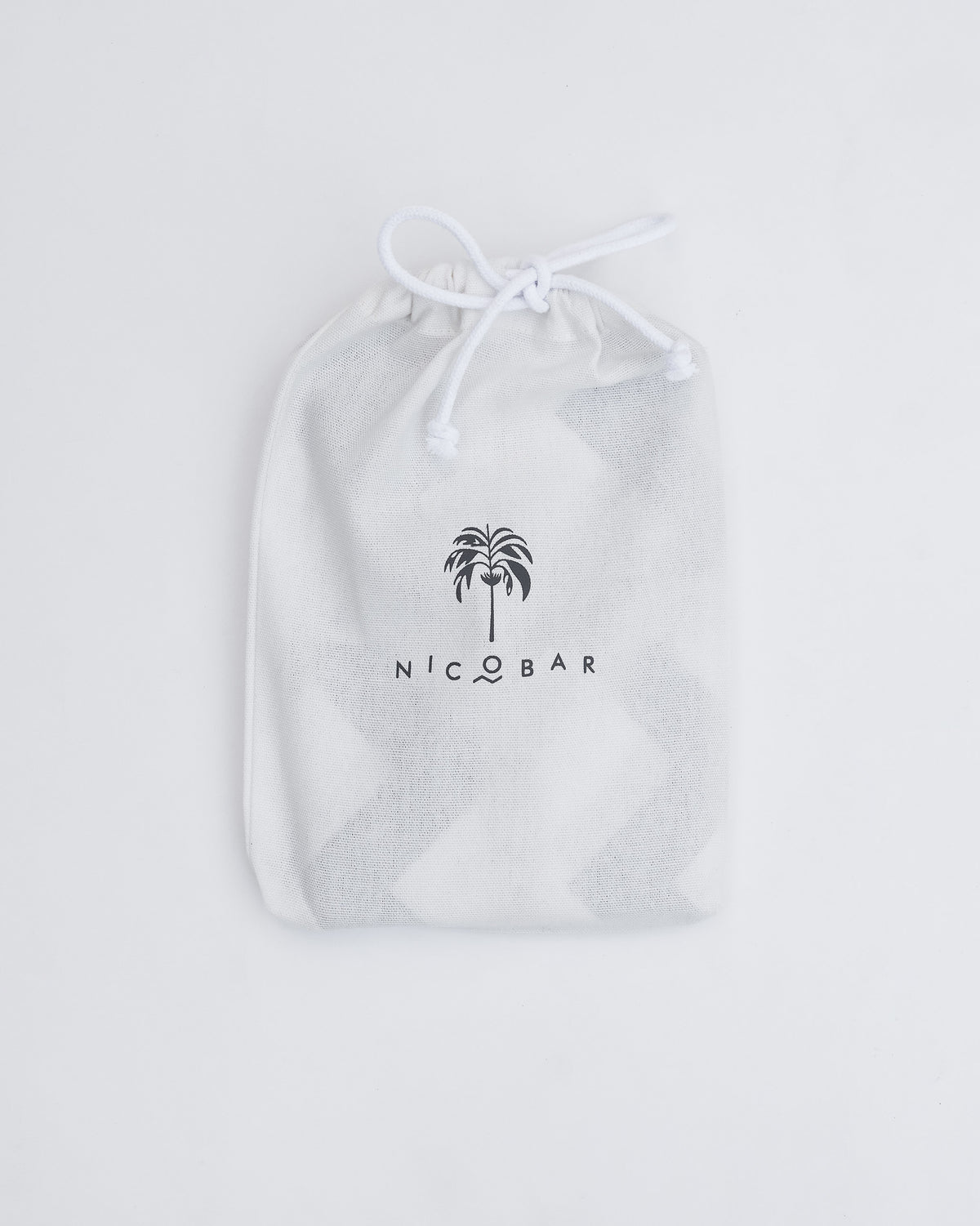 Colombo Wave bedsheet in a white Nicobar drawstring pouch.