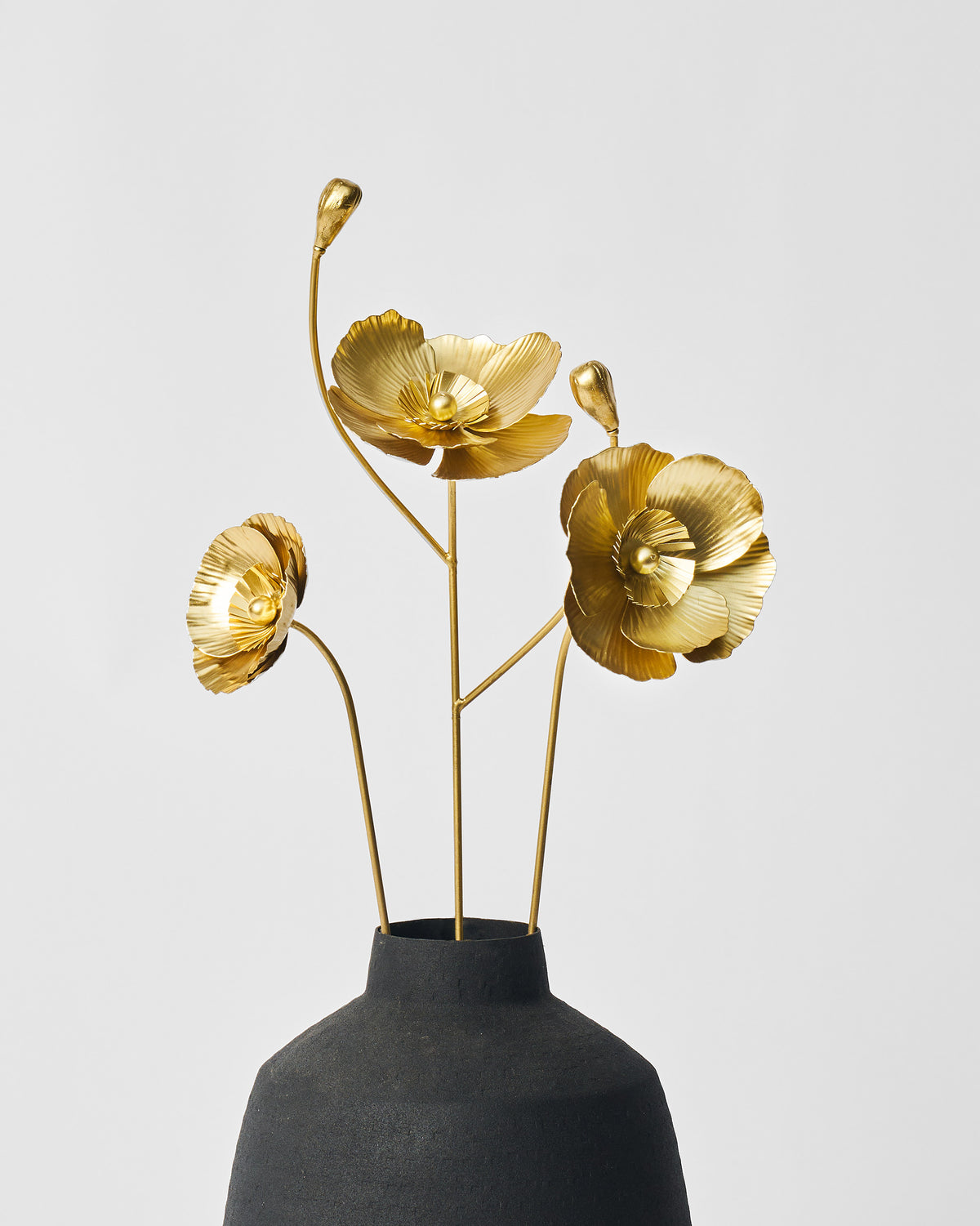 Gold metal Poppy accent stems with open blooms in a matte black vase.