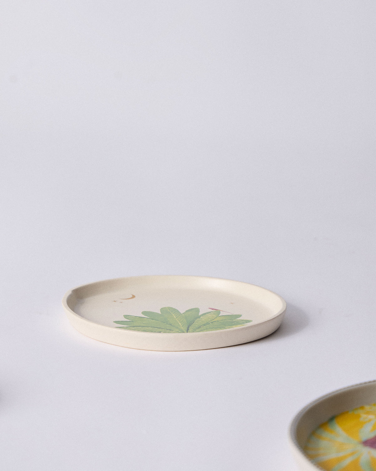 Angled view of the Ceylon Trail Dessert Plate with a green palm motif.