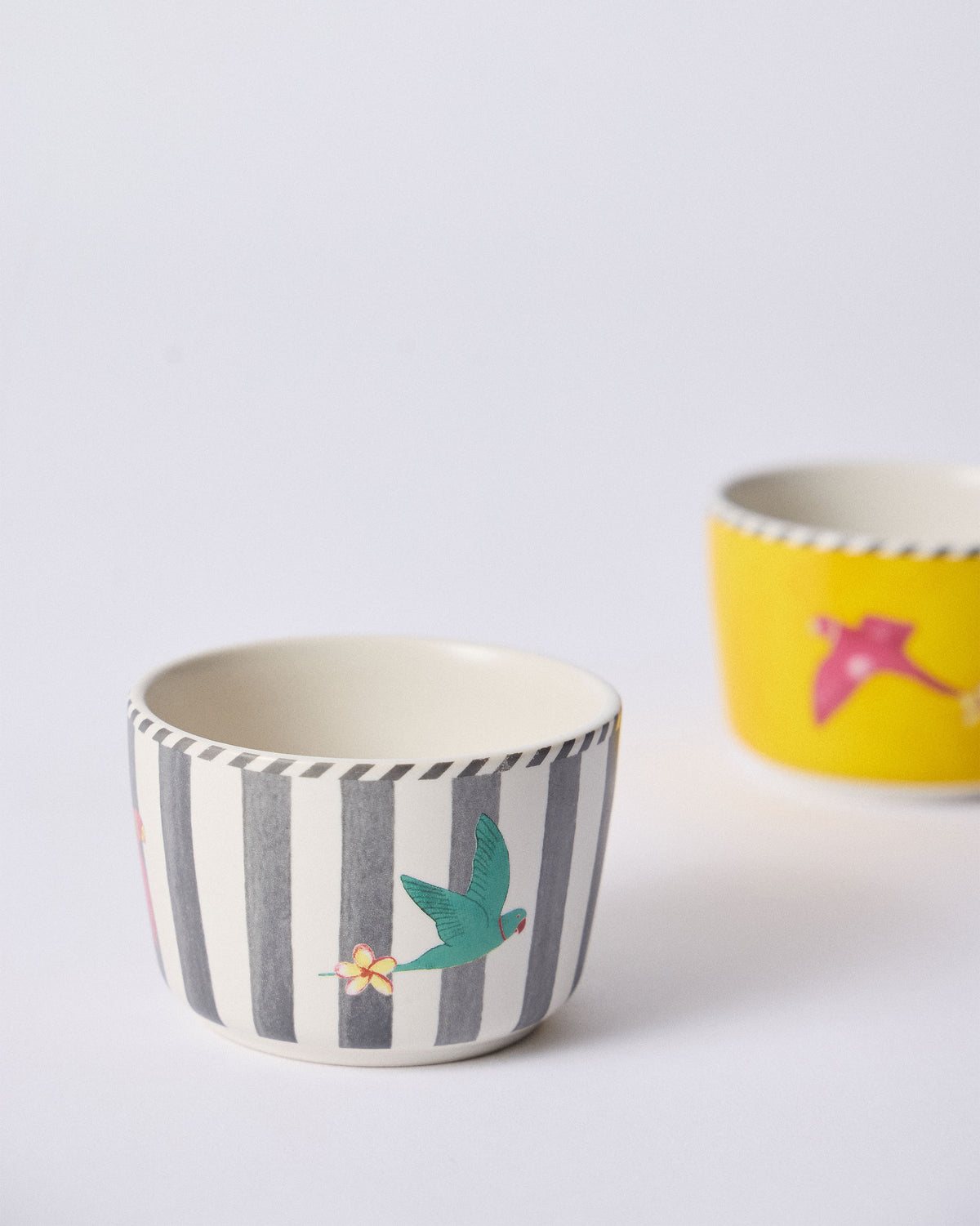 Close-up of a striped Ceylon Trail Nut Bowl with a teal bird and flower.