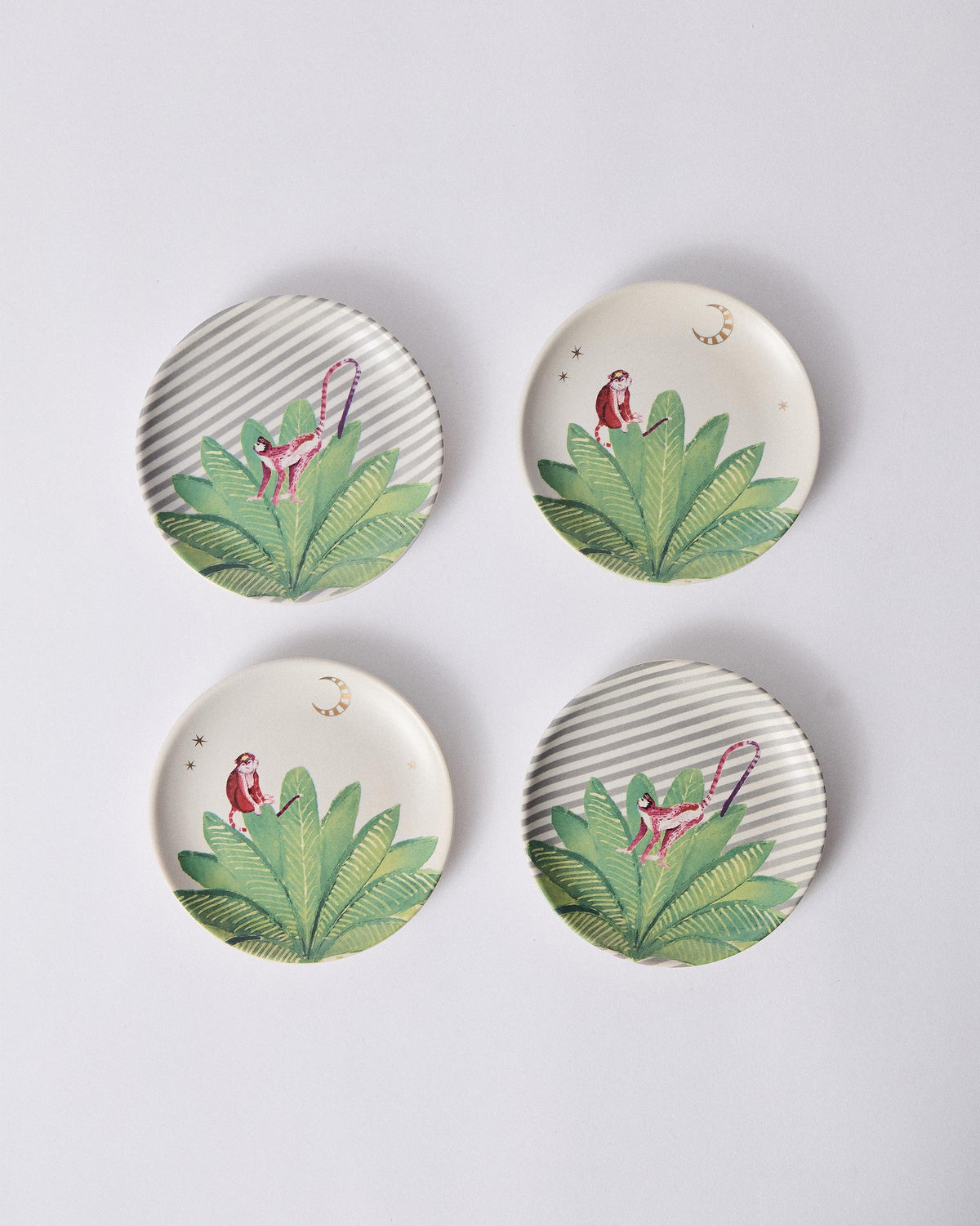 Ceylon Trail tea plates alternating striped and cream grounds with pink monkeys.