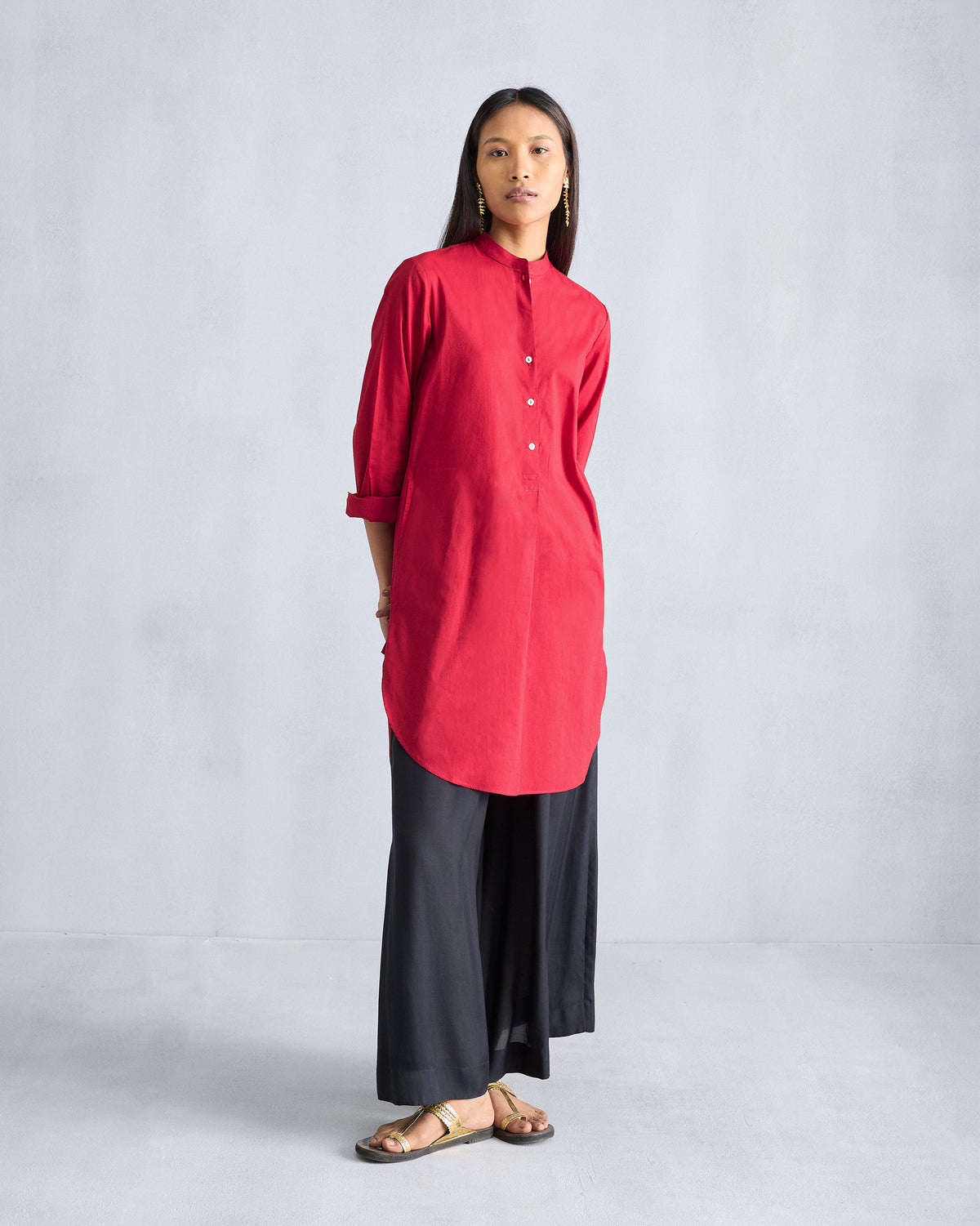 Person wearing a red mid-length kurta with a mandarin collar and curved hem.