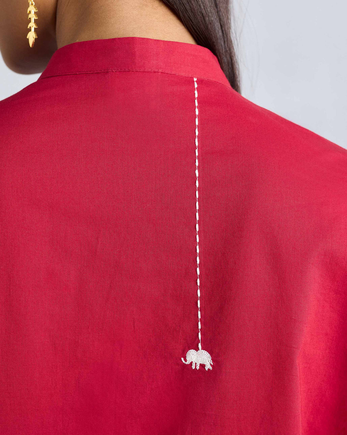 Close-up of a white embroidered elephant on a red kurta.